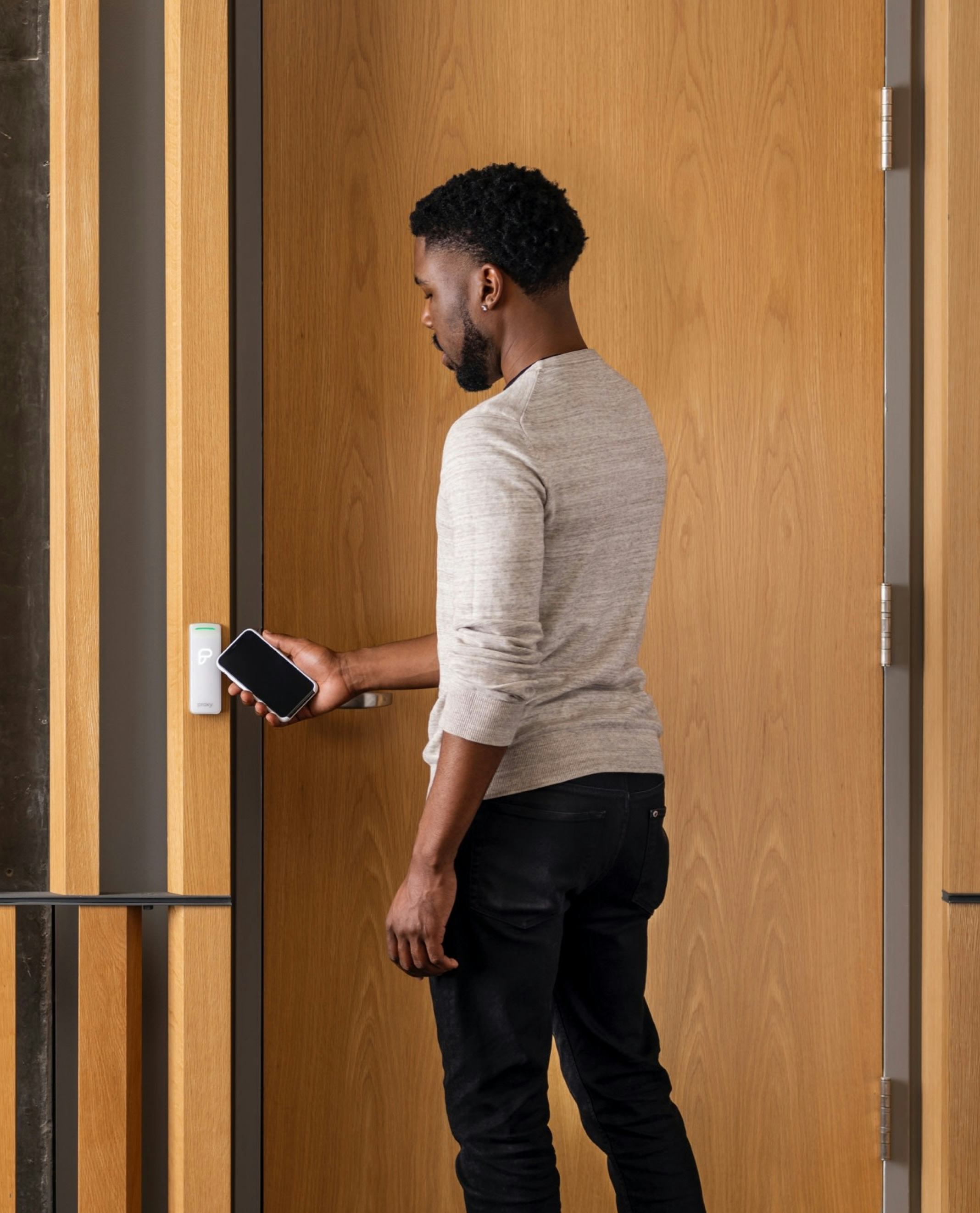 Man tapping his phone on a door reader to open it