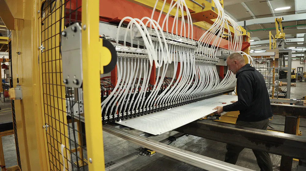 A man tending an automated riveting system