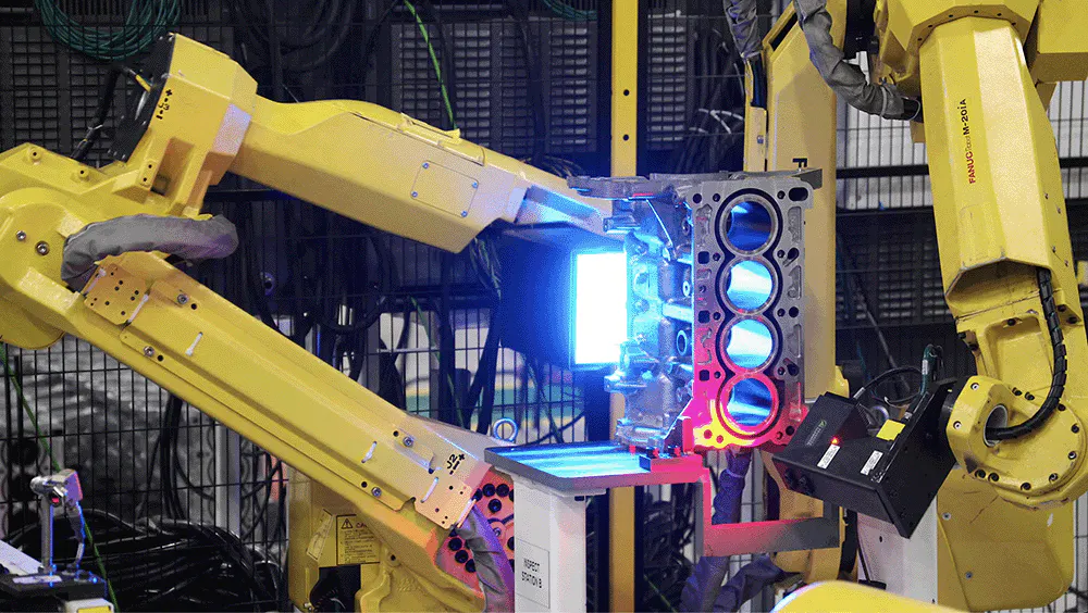 A yellow robot inspecting an engine block