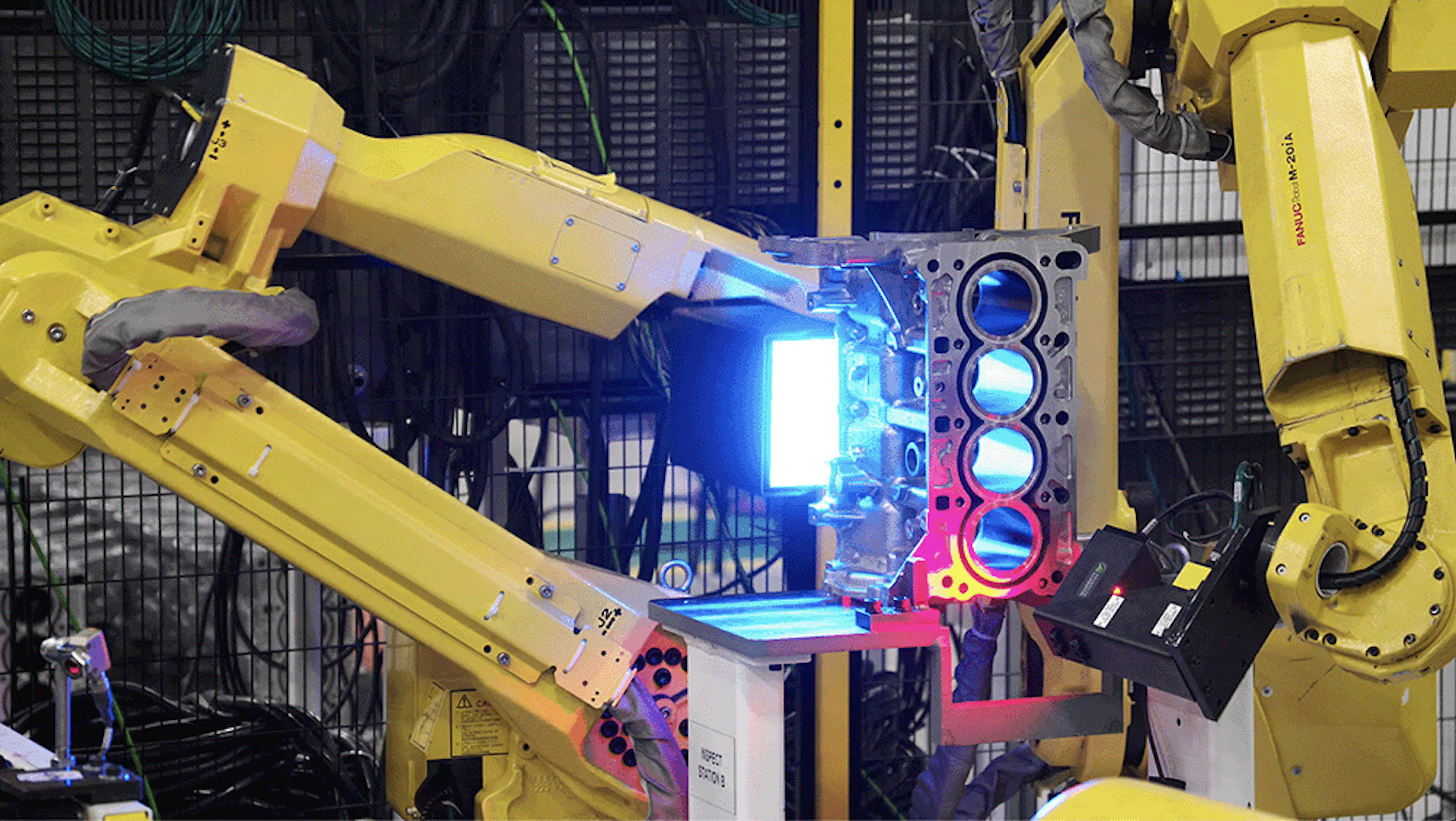 A yellow robot inspecting an engine block