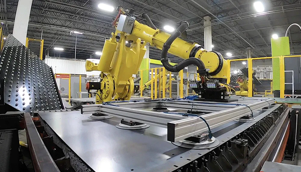 A yellow robot handling sheet metal