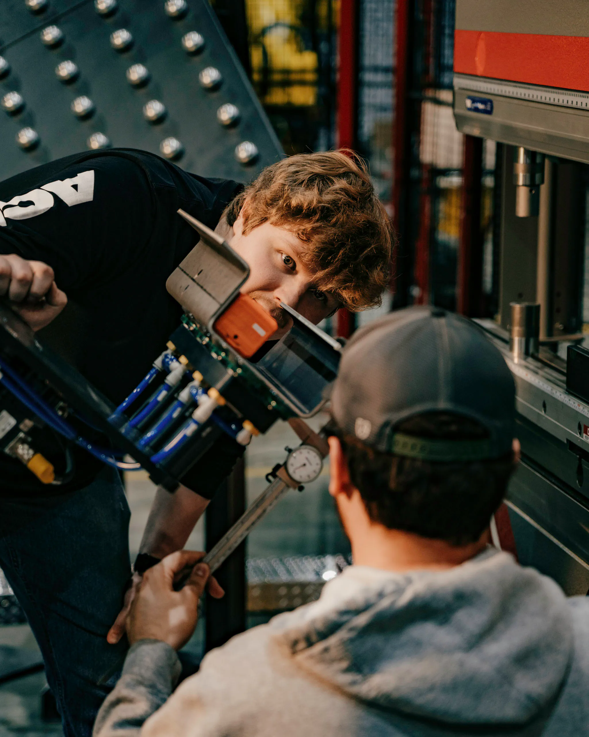 two people working on the end of arm tooling of a robotic press brake
