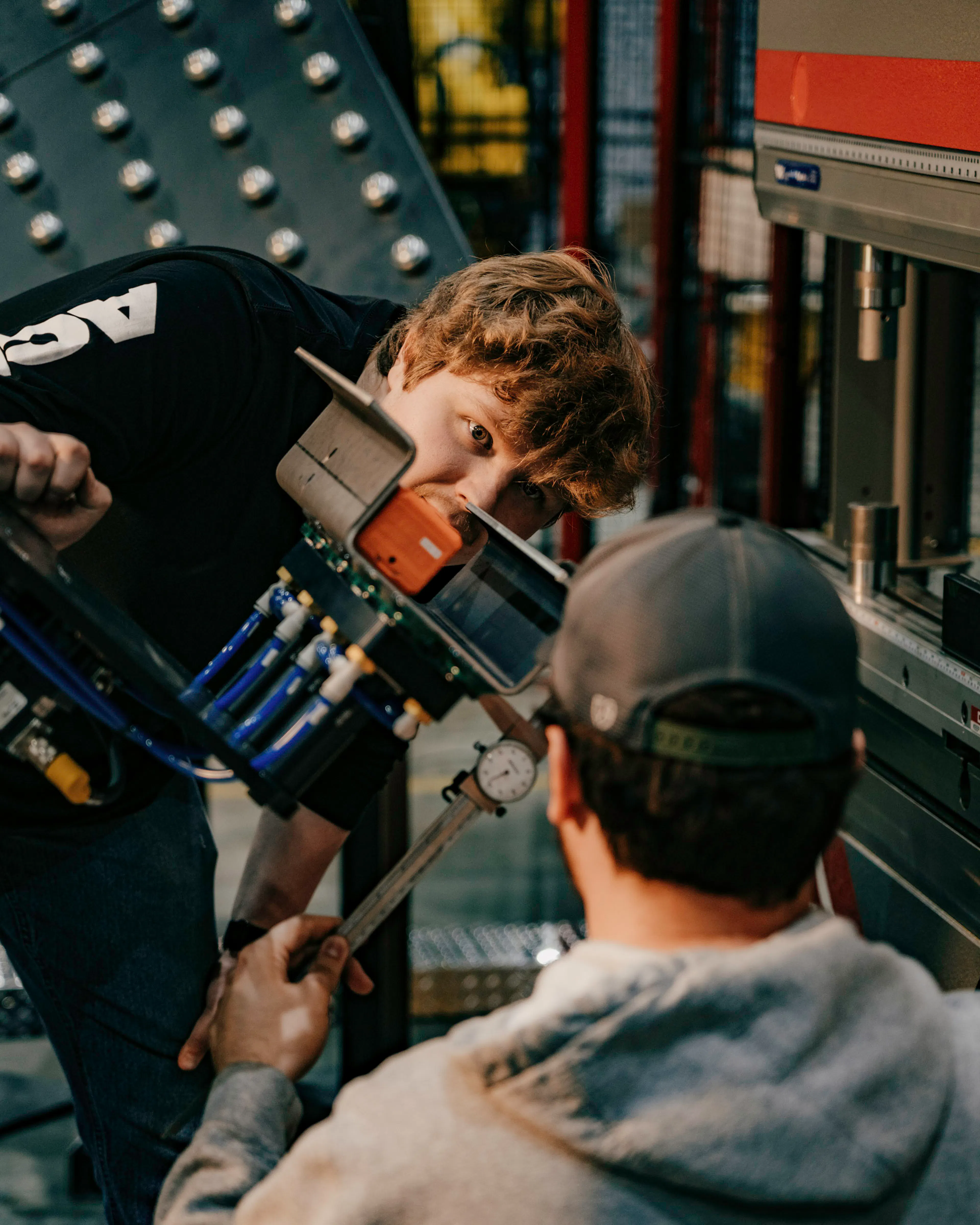 two people working on the end of arm tooling of a robotic press brake