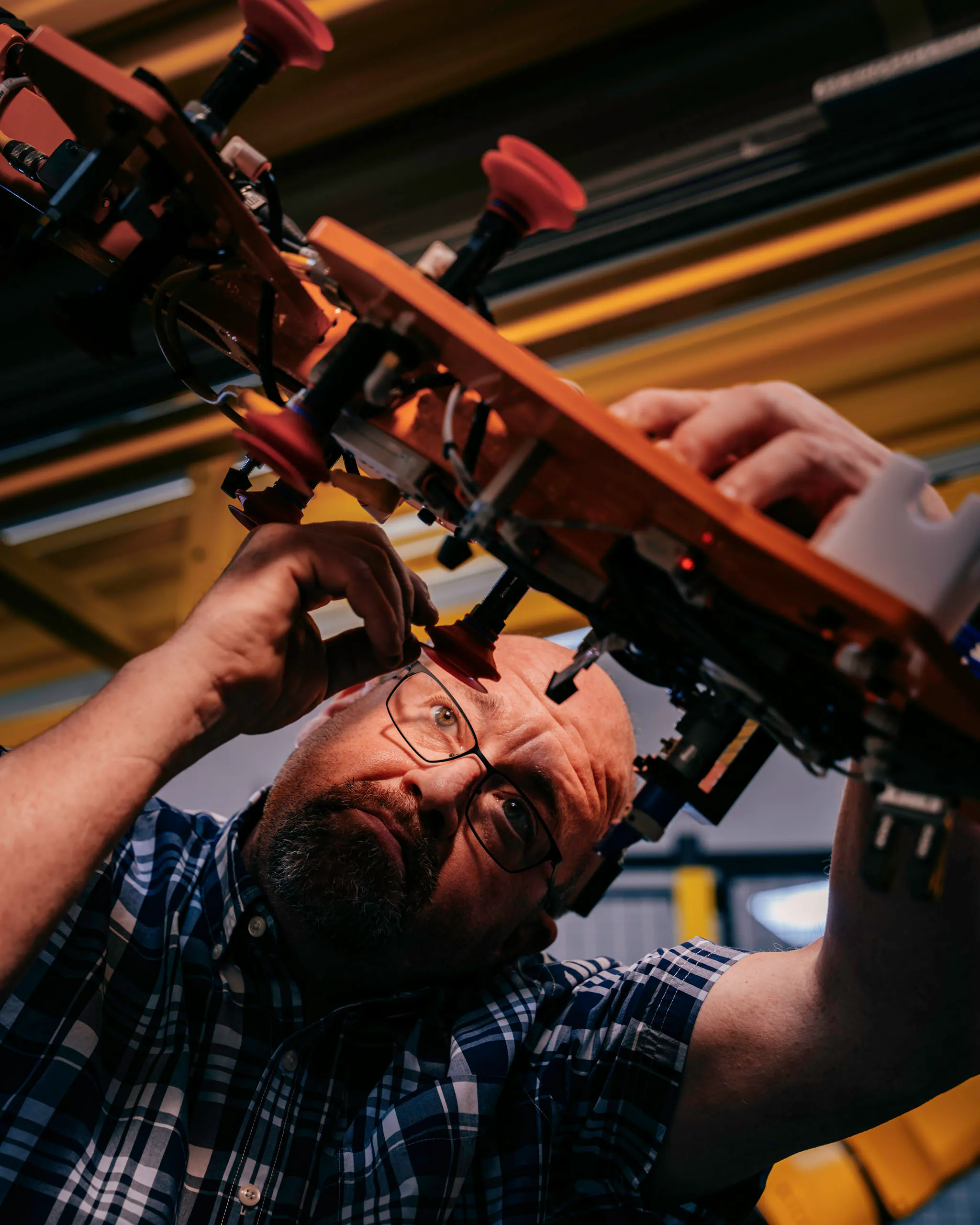 A man working on a custom end-of-arm tooling on a FANUC robot