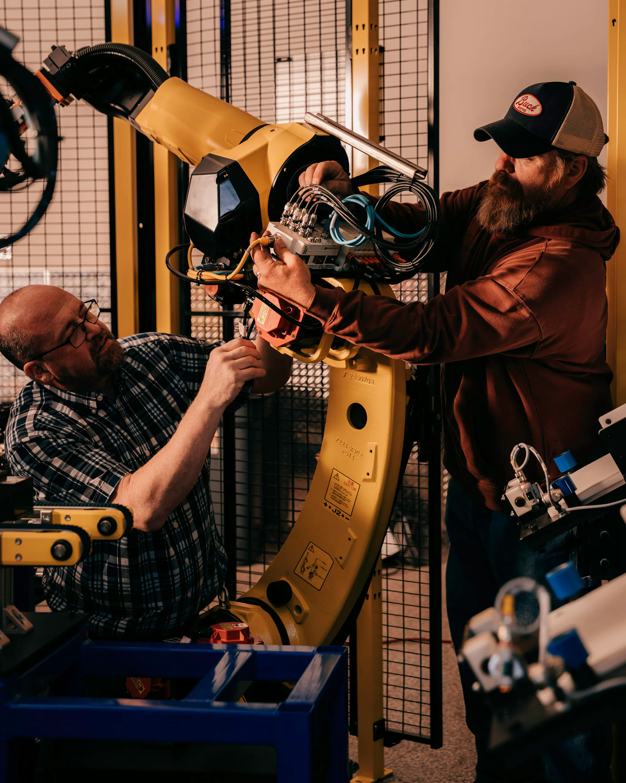 Two Acieta team members working on a yellow FANUC robot