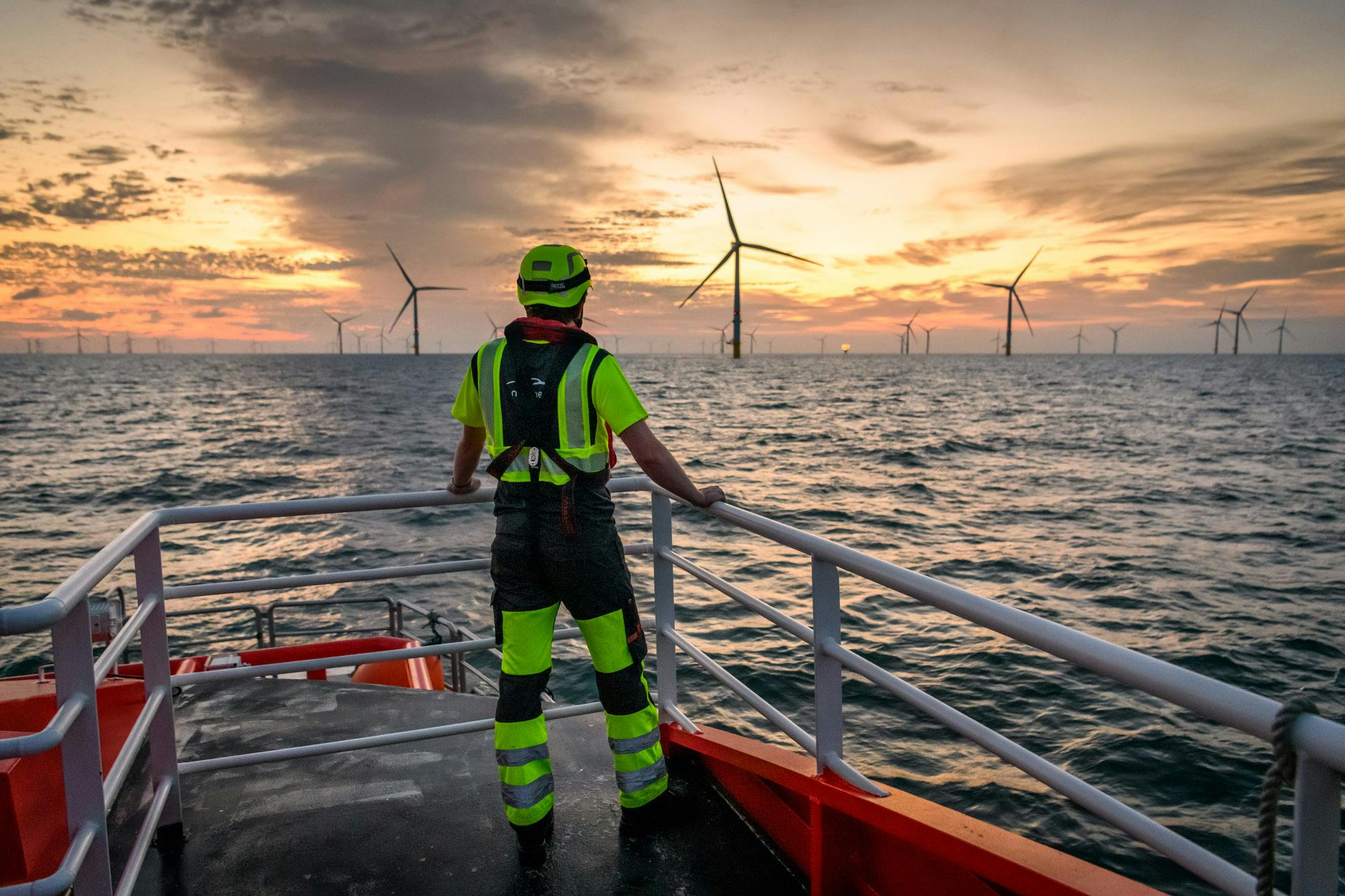 a man in a uniform overlooking an off-shore wind farm from a boat