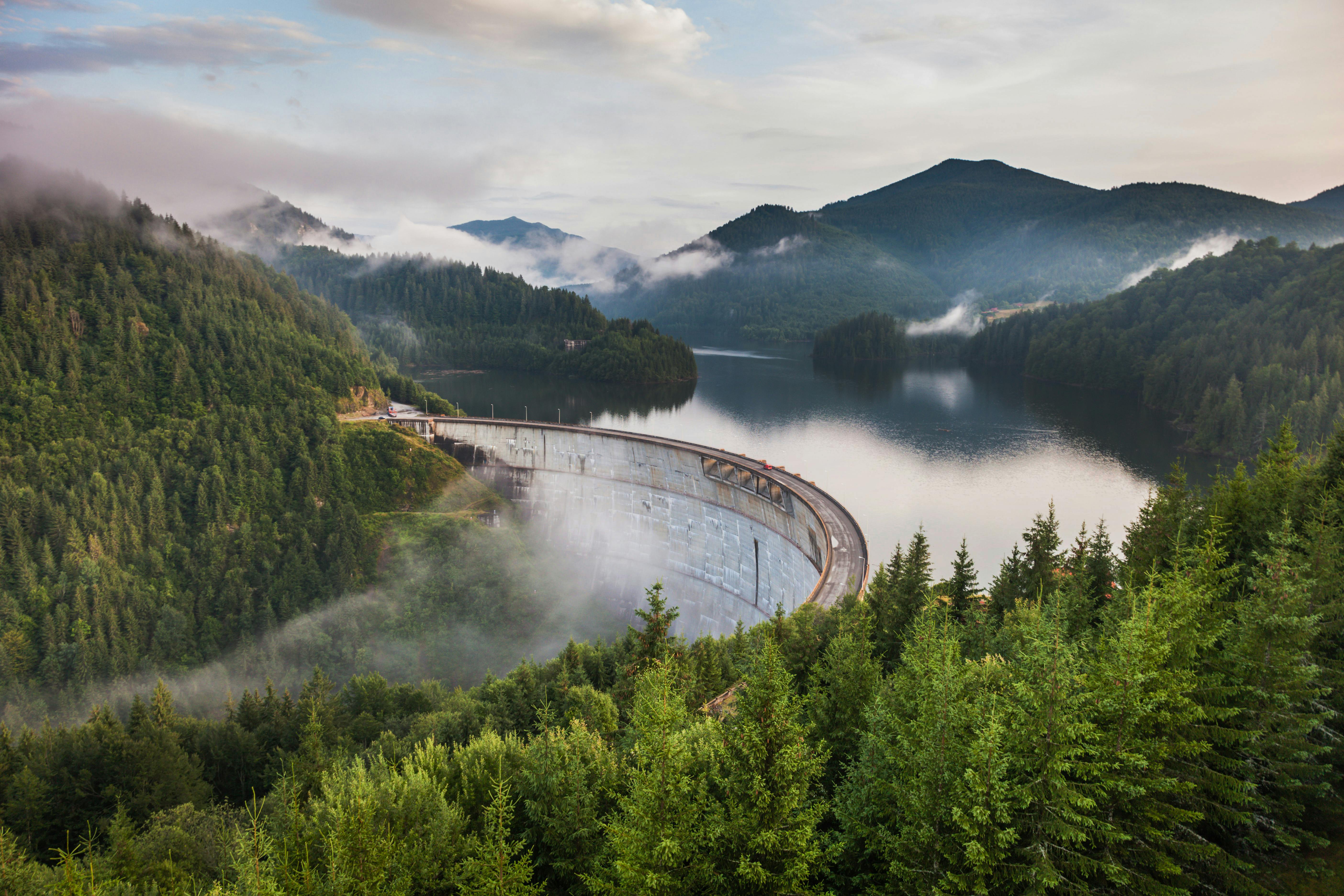 A picture a scenic mountain and a river with a hydroelectric dam 