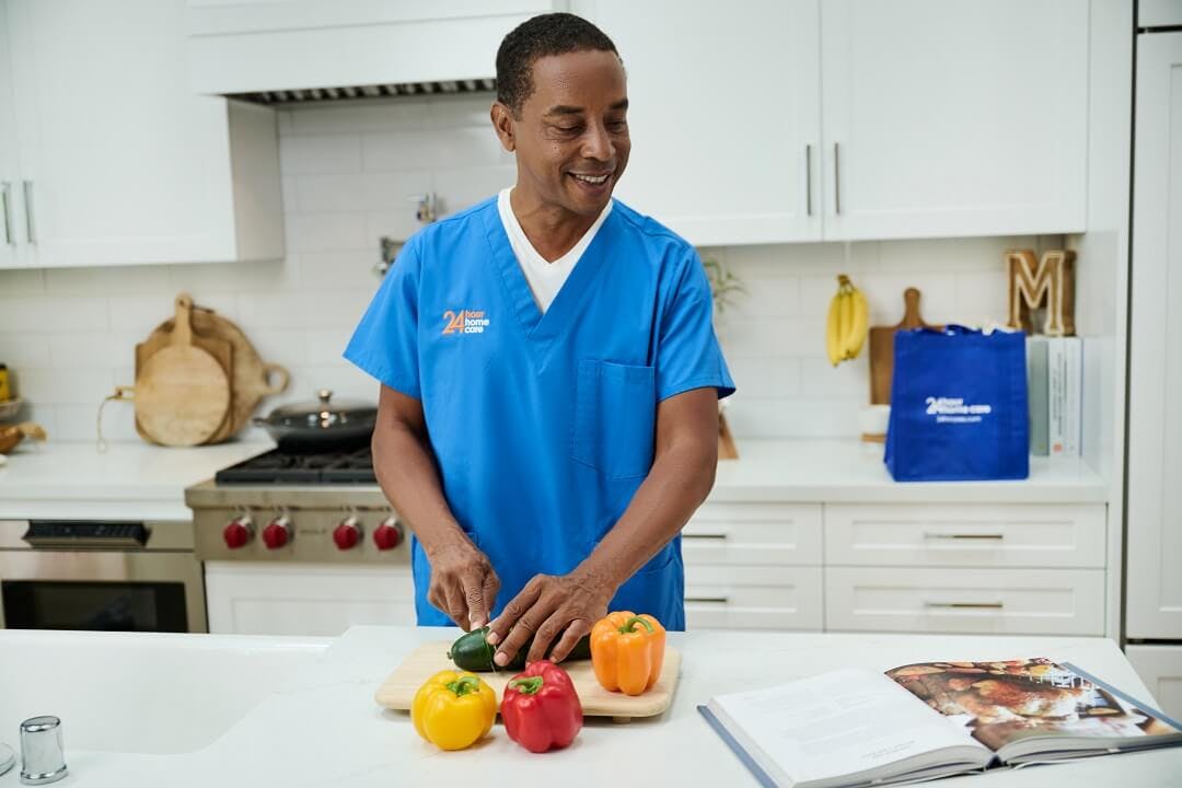 A caregiver cuts peppers while he meal preps for his client.