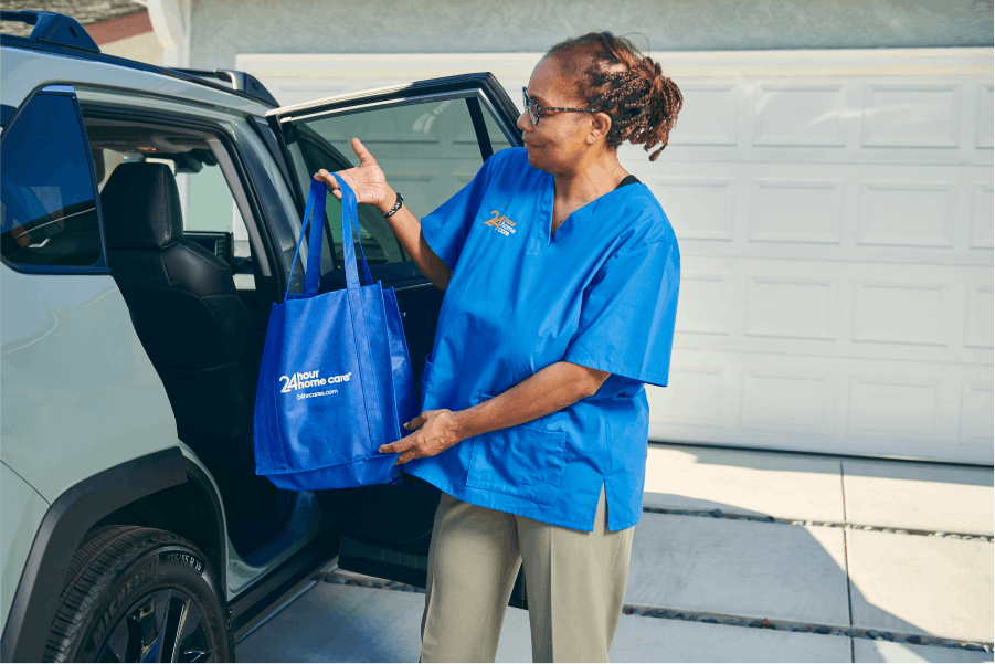A caretaker carrying bags out of a clients car