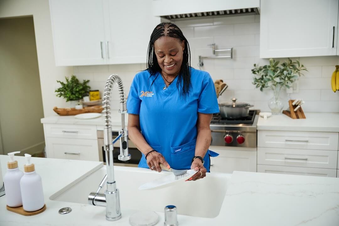 A caregiver helps her client by doing dishes after meal prepping in their home for the coming week.