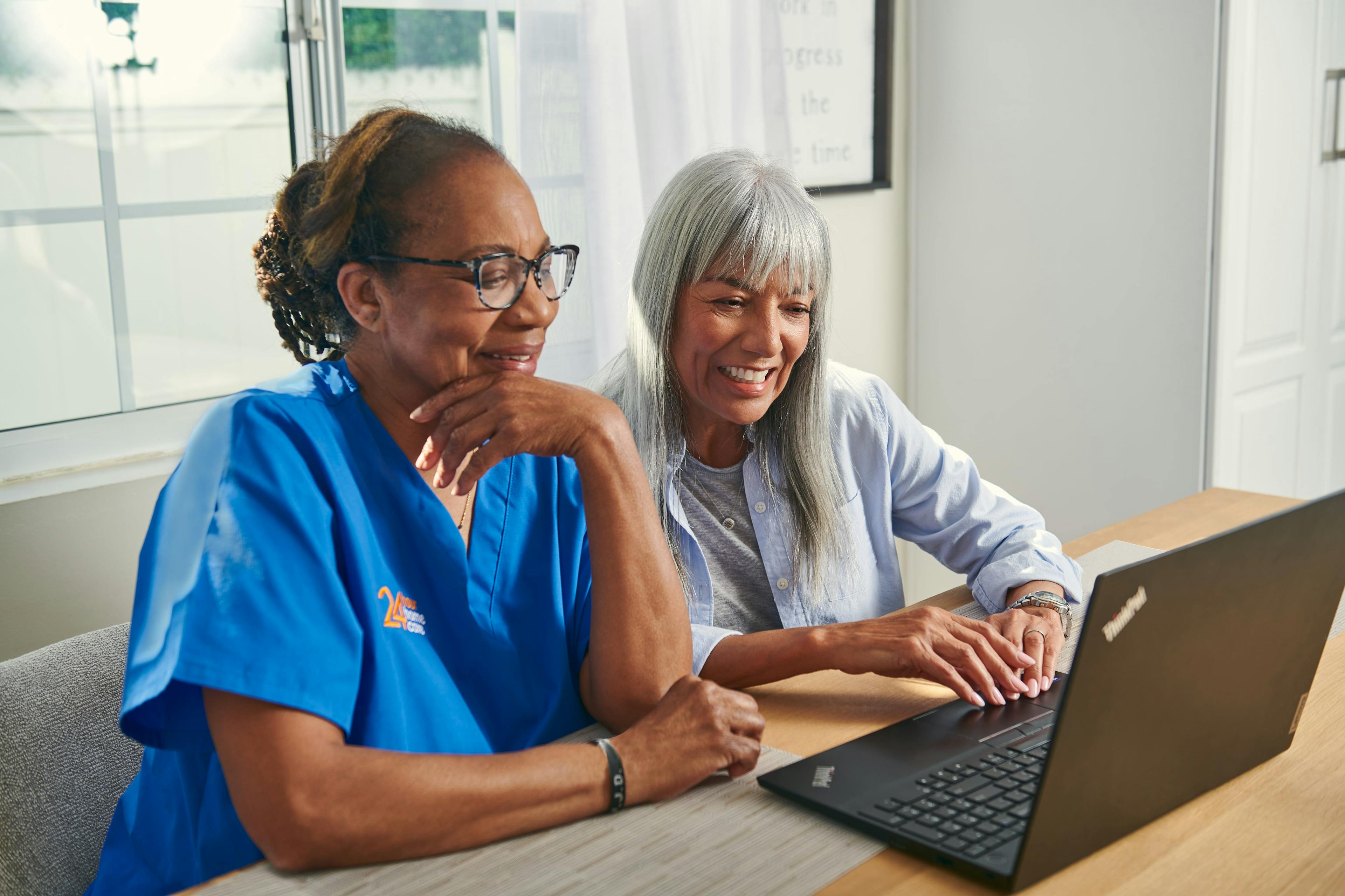 A caregiver and a senior using a laptop together