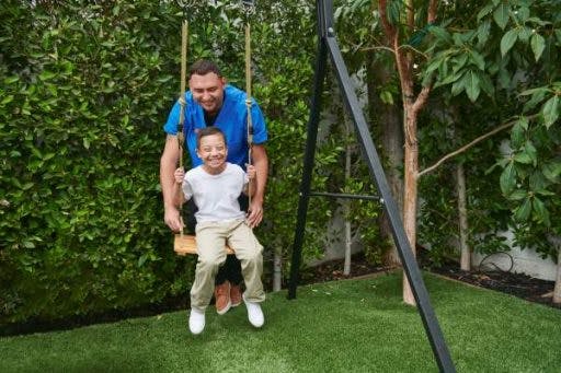 A child with disabilities and his care provider play in the back yard.