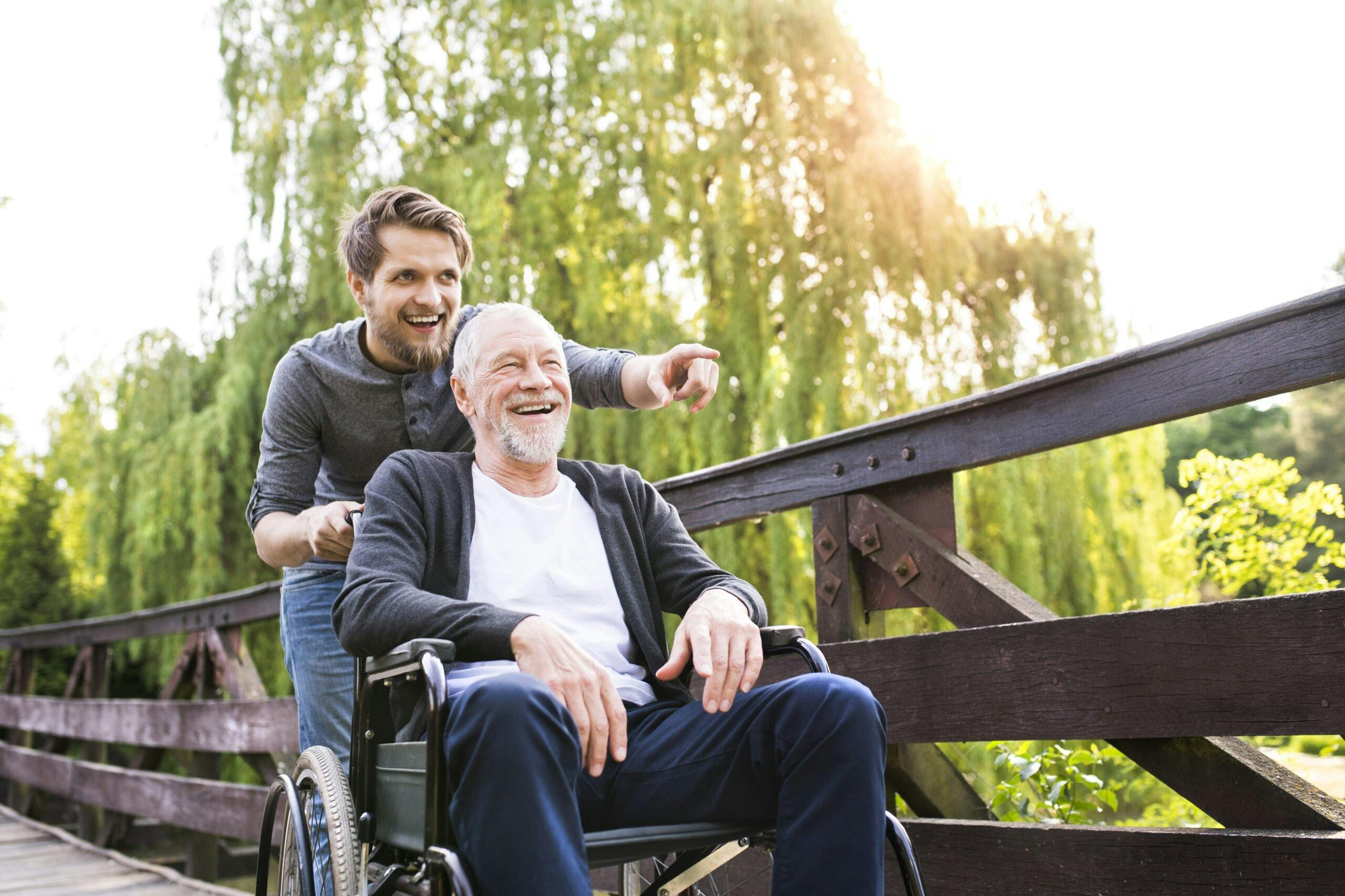 Hipster,Son,Walking,With,Disabled,Father,In,Wheelchair,At,Park.