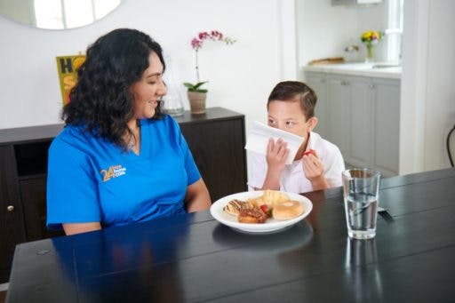 Image of a caregiver preparing a healthy meal for a client who is a young boy with a disability.