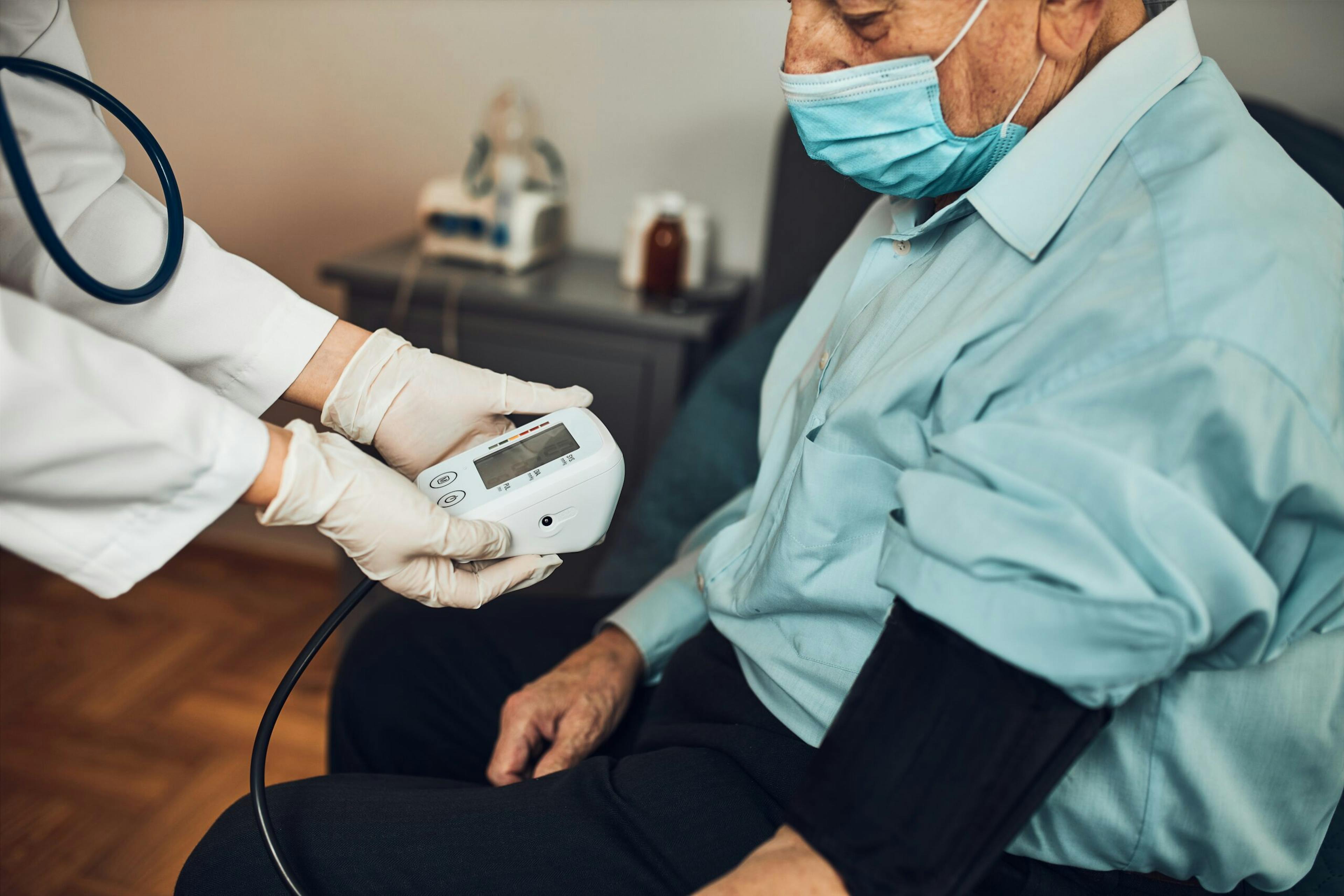 Doctor carying out blood pressure test and heart rate of senior man. Checking health condition elder patient suffering from arterial hypertension