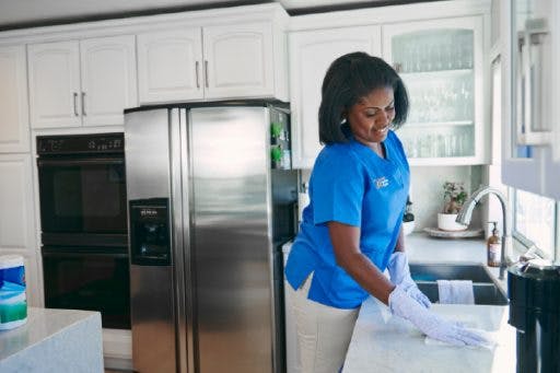 Image of a caregiver doing light cleaning in a client’s kitchen.