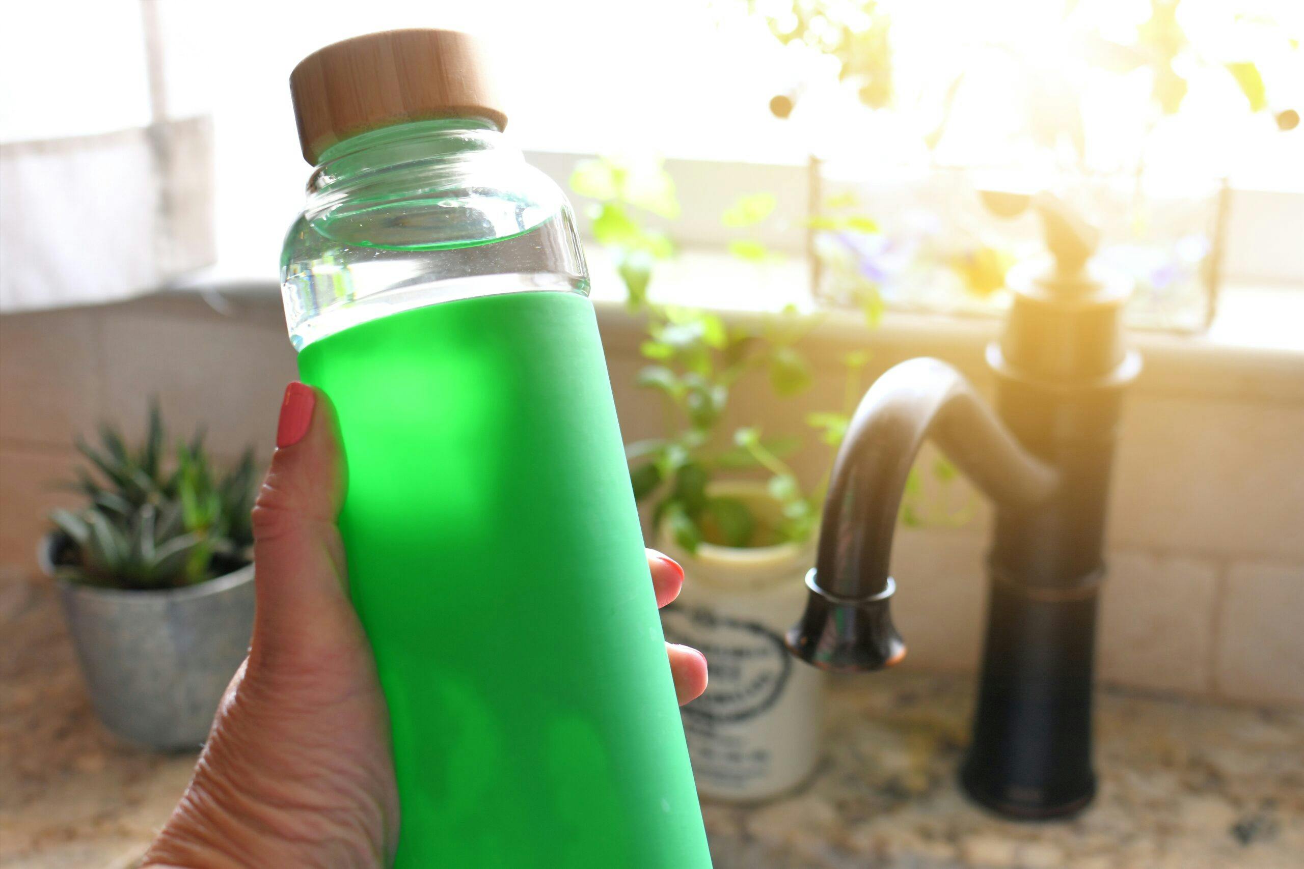 female-holding-a-blank-reusable-water-bottle-after-filling-it-in-the-kitchen-sink-mock-up-add-your_t20_6Yn0X2