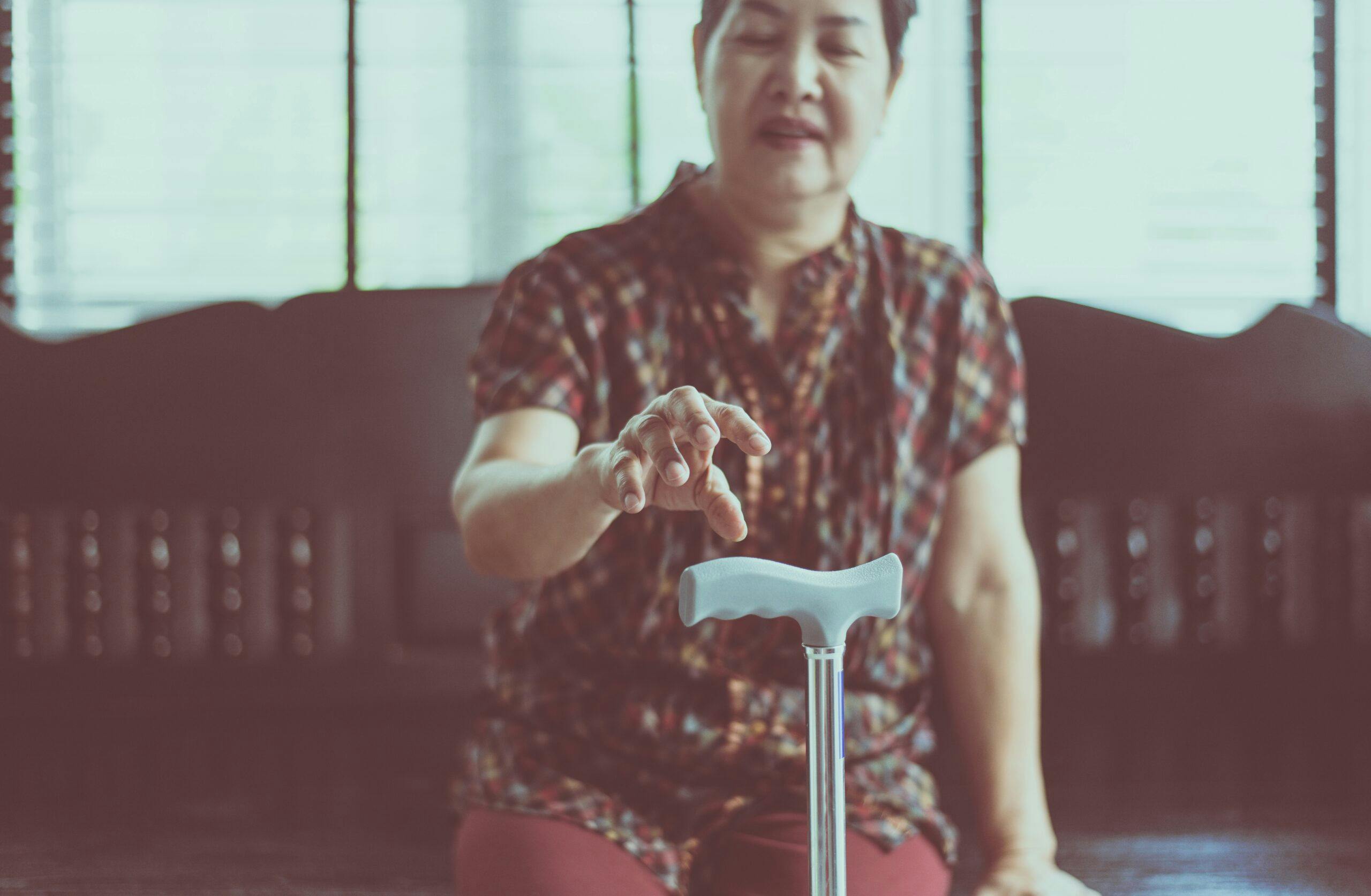 Elderly woman suffering with parkinson’s disease symptoms on hand