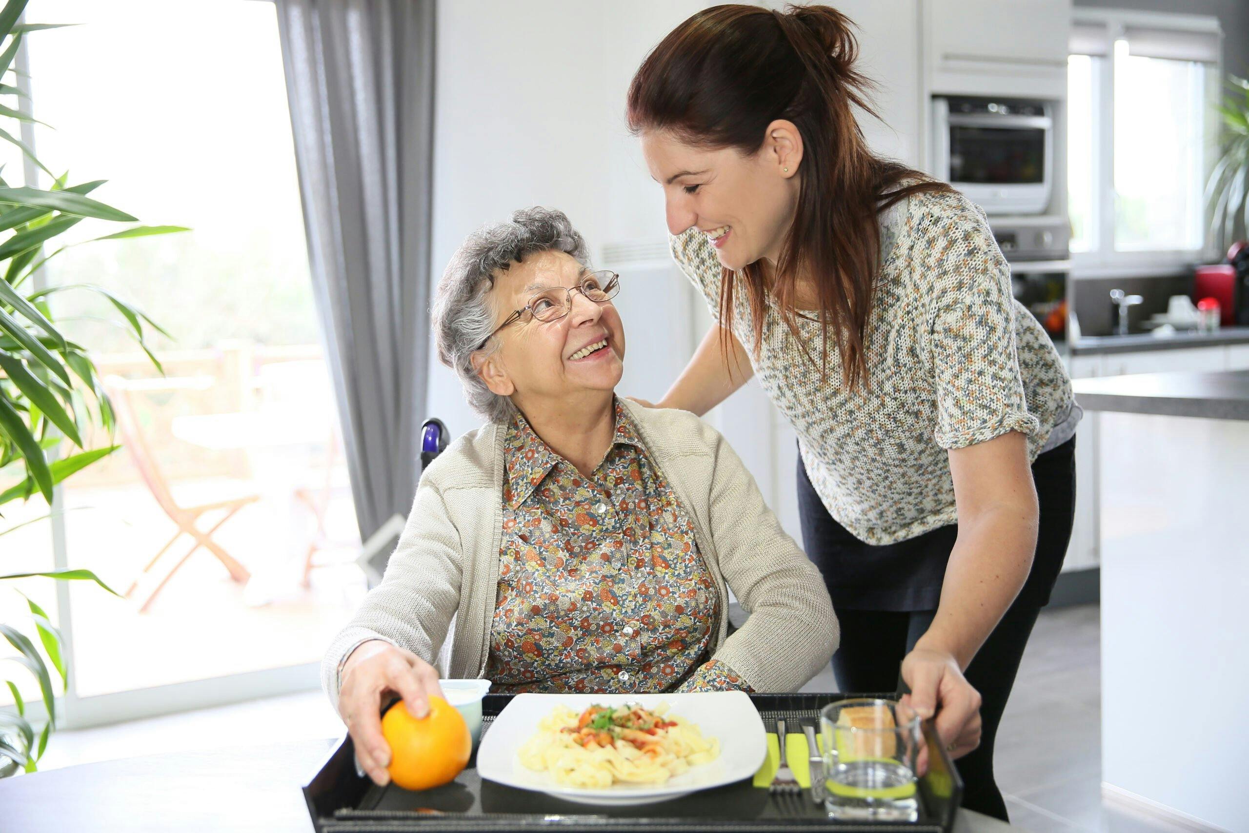 Homecarer preparing lunch for elderly woman