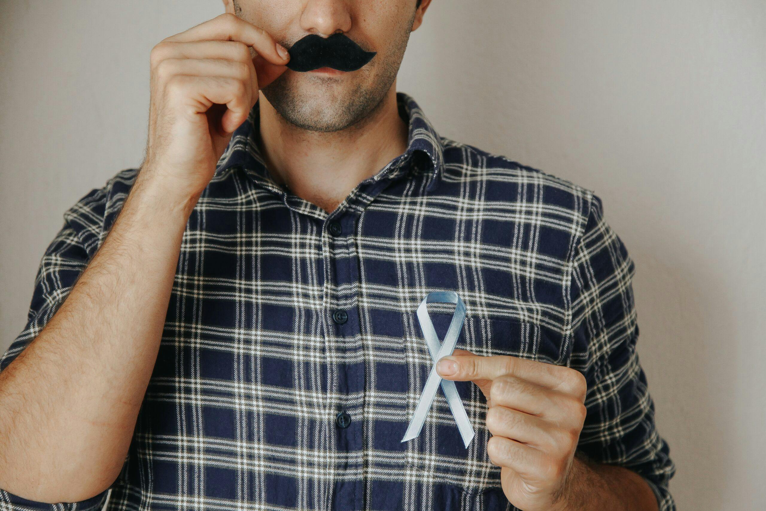 mans-hand-holding-a-blue-ribbon-and-moustache-in-front-his-face-prostate-cancer-awareness-month-mens_t20_LzgWgo
