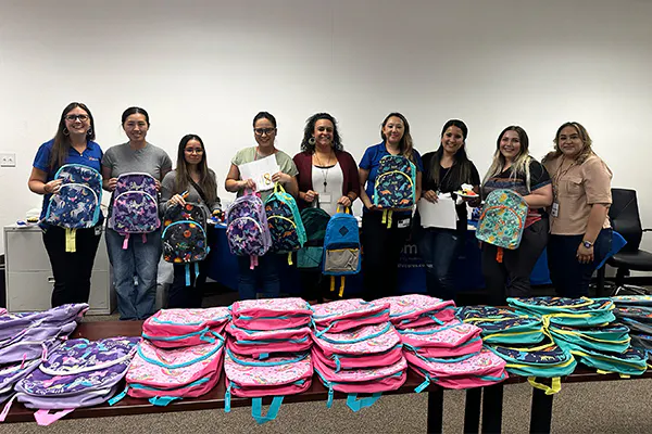 24 Hour Home Care’s team poses with Service Coordinators and backpacks that will be given away to families served by the Regional Centers.