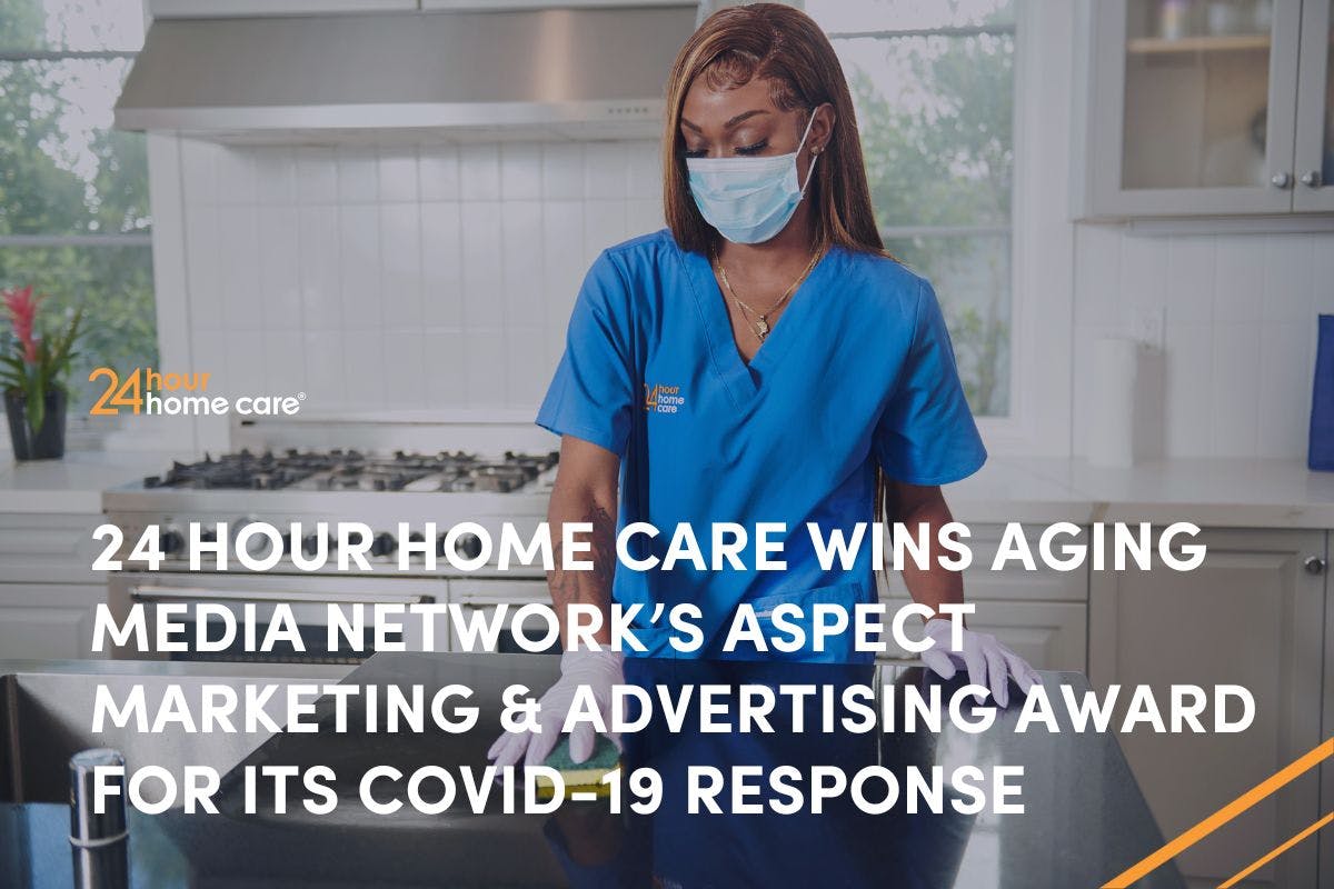 A caregiver in PPE gear cleans a client's kitchen counter.