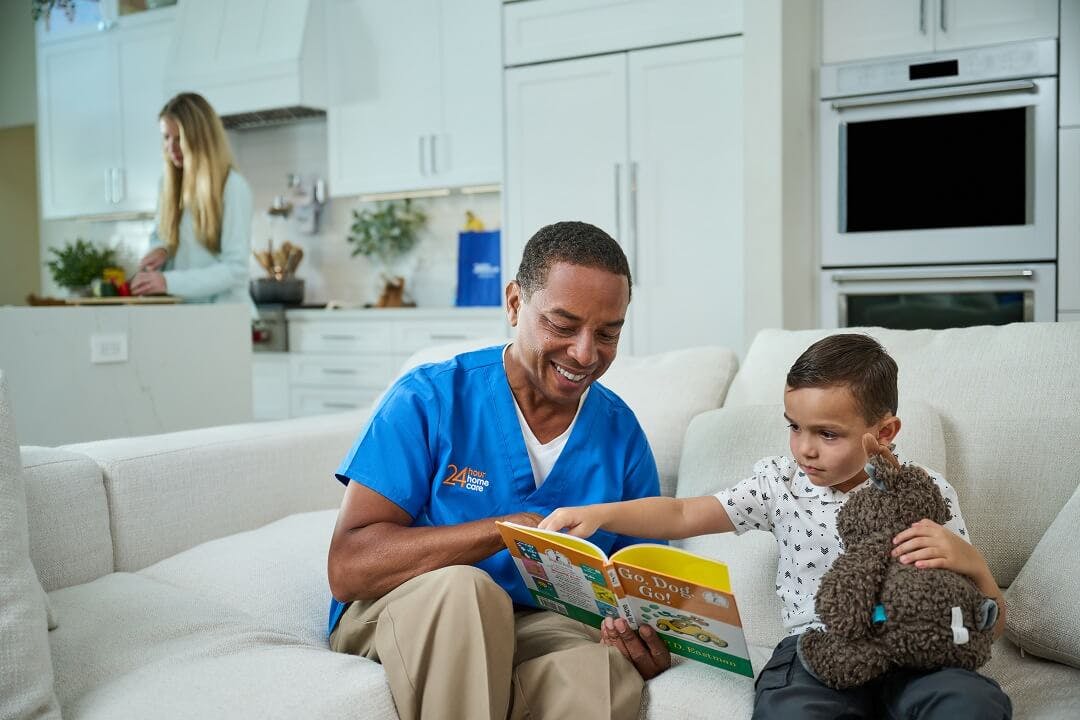 A care provider reads a book to the child he's providing care for.