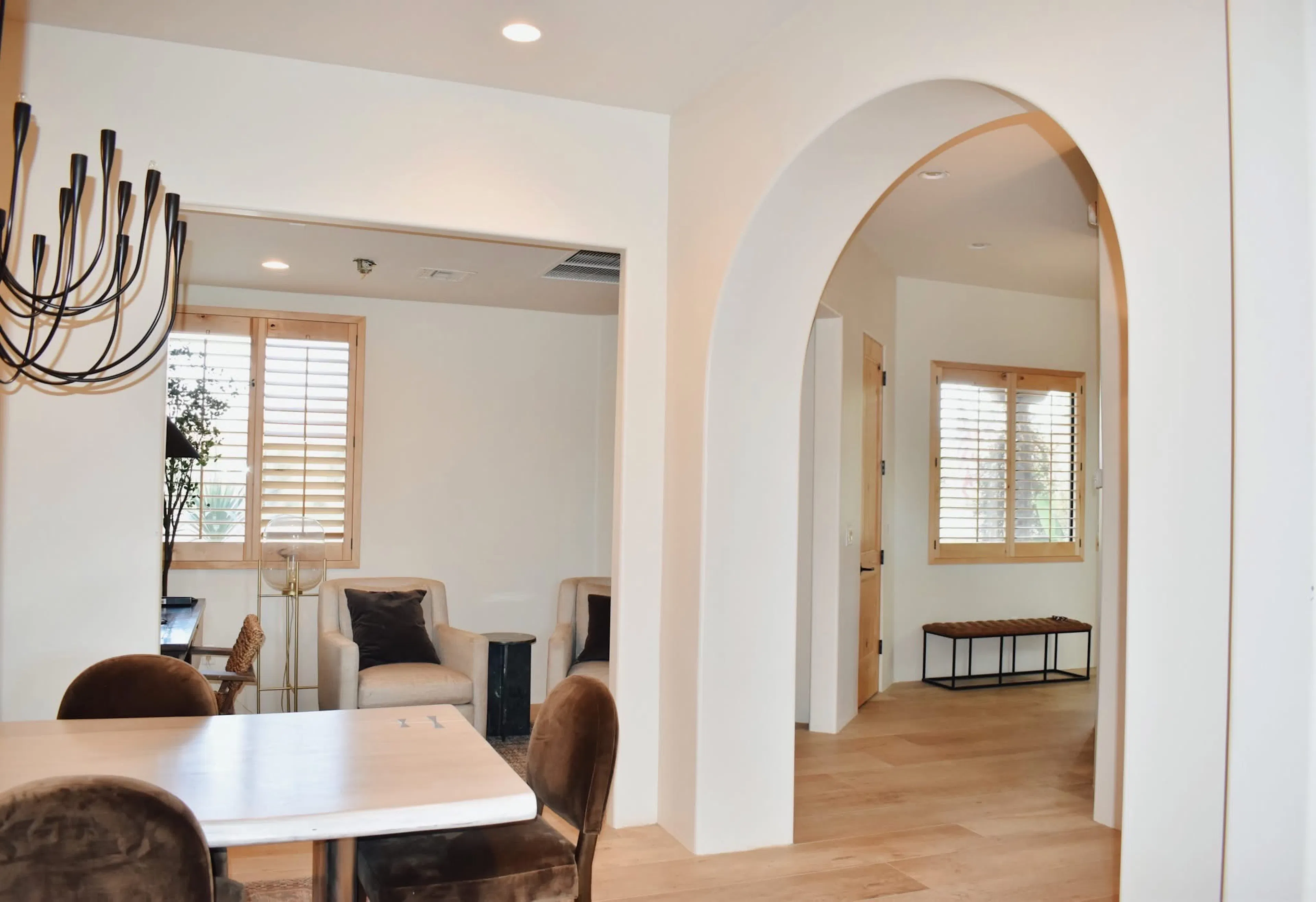 Bright remodeled living and dining space with arched openings, light wood floors, and coordinated trim.