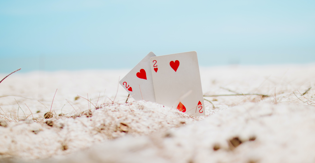 Two two of hearts playing cards in the sand