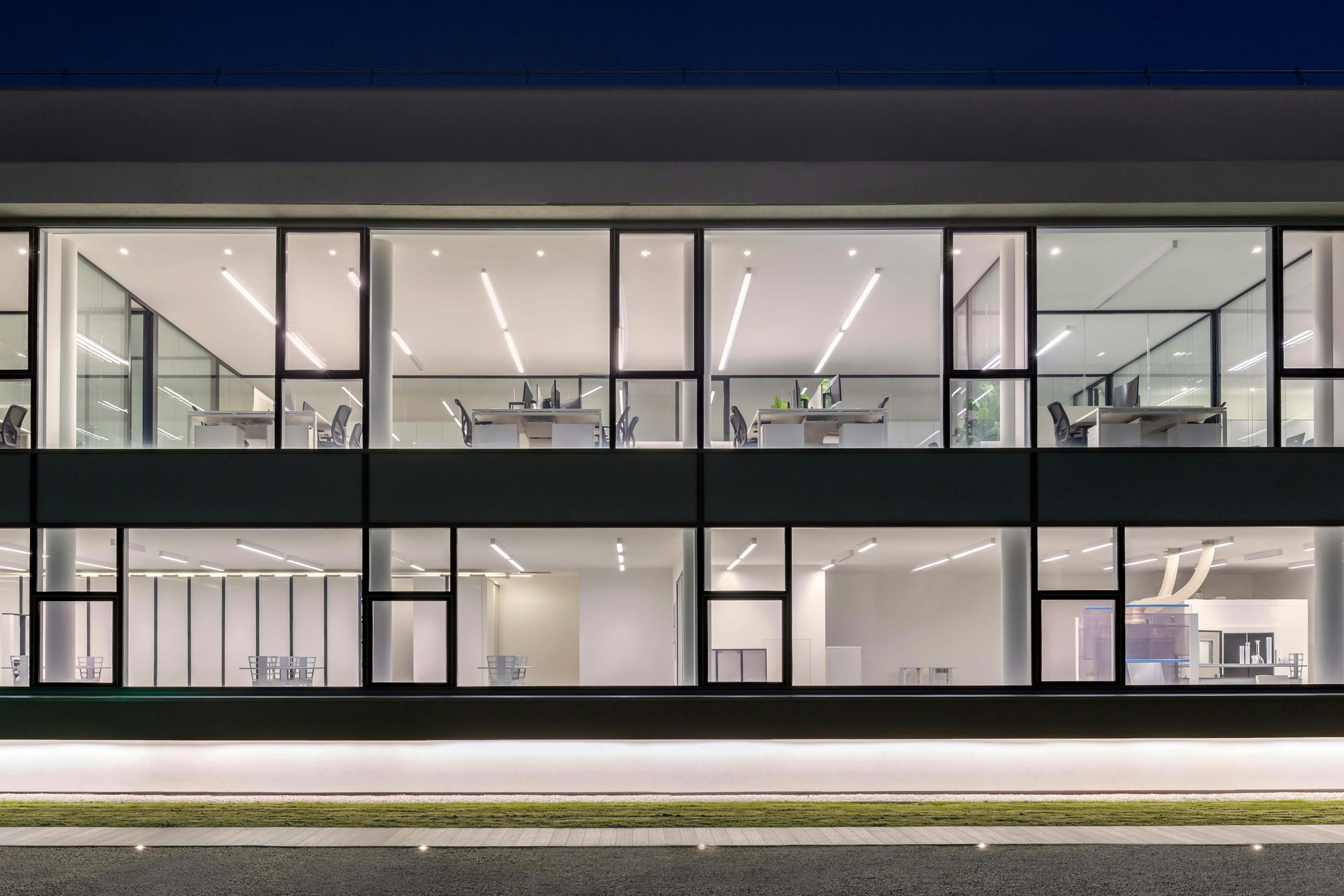 3B office building at night with large illuminated windows and visible workstations
