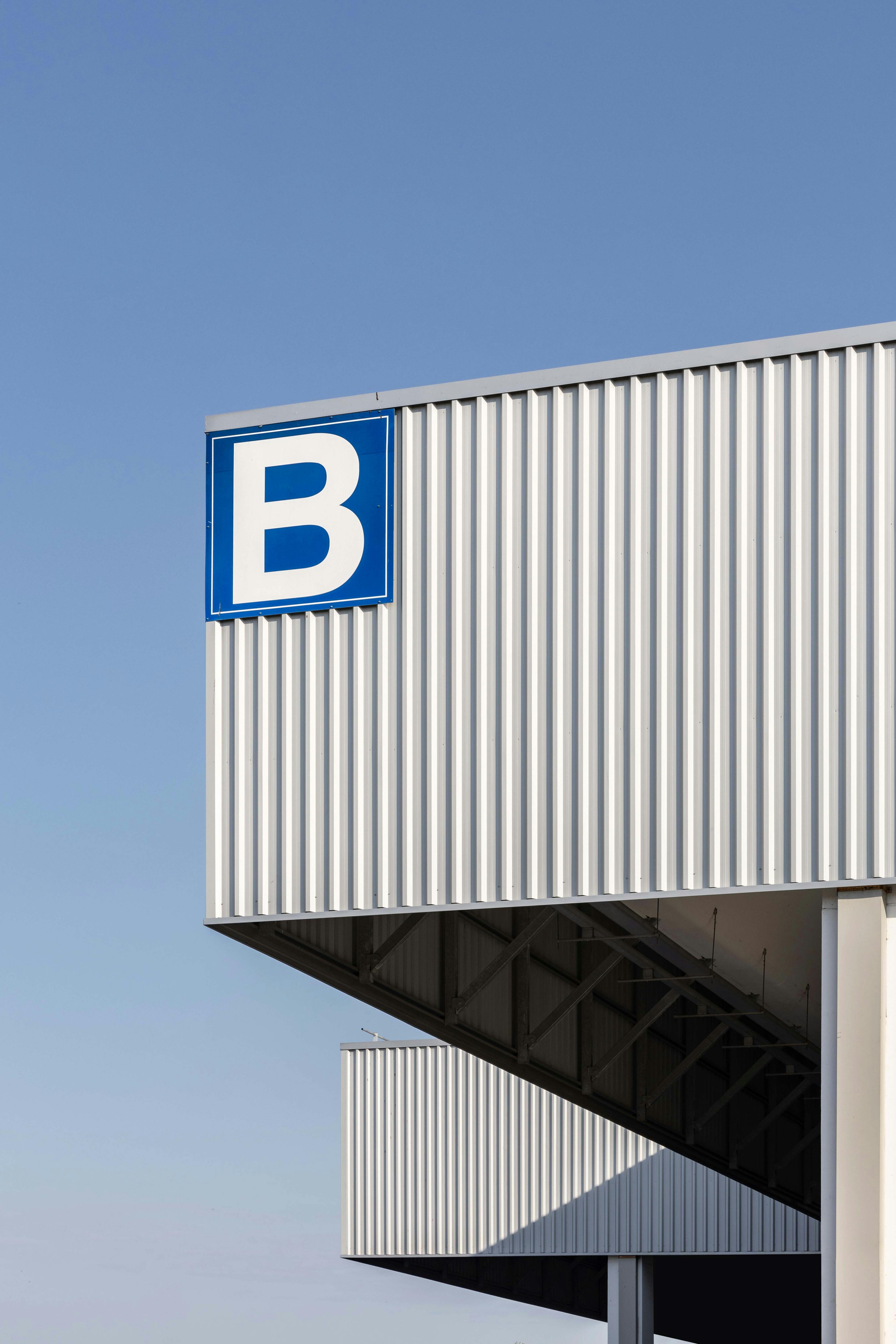 Geometric facade of building 3B with clear blue sky and prominently displayed logo sign