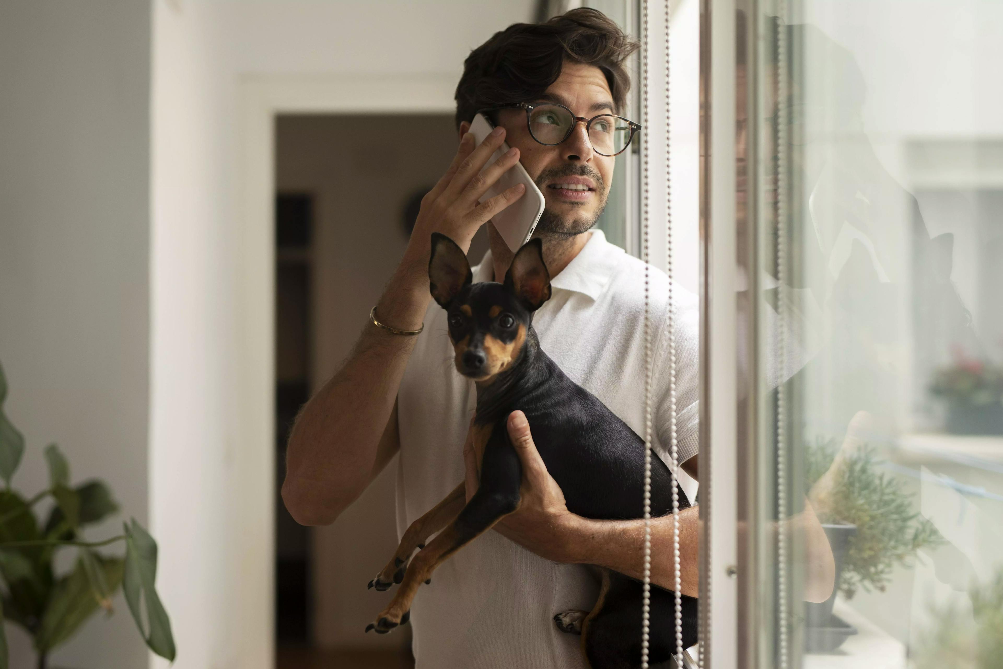 чоловік тримає собаку на руках та розмовляє по телефону