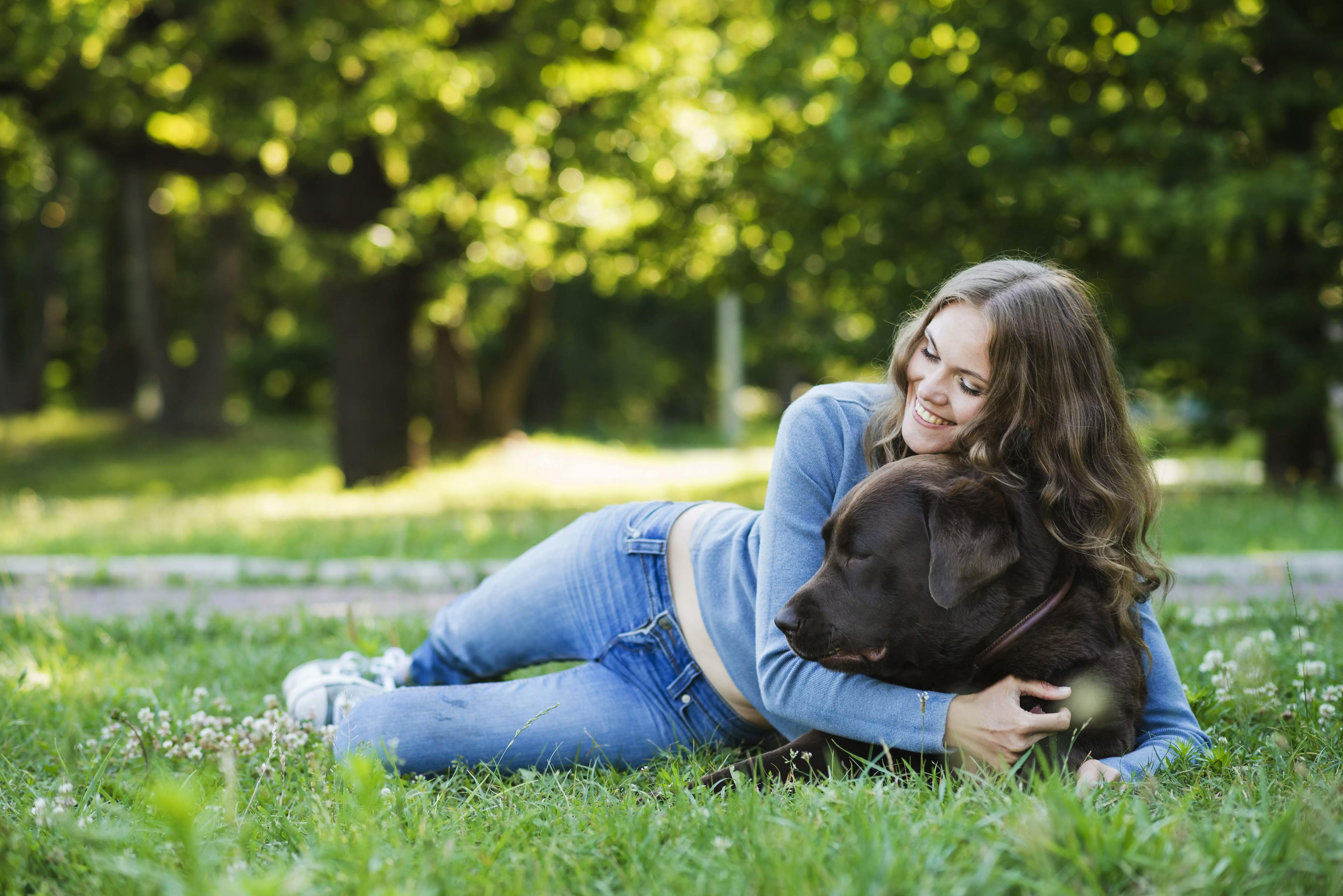 дівчина обіймає свою собаку в парку