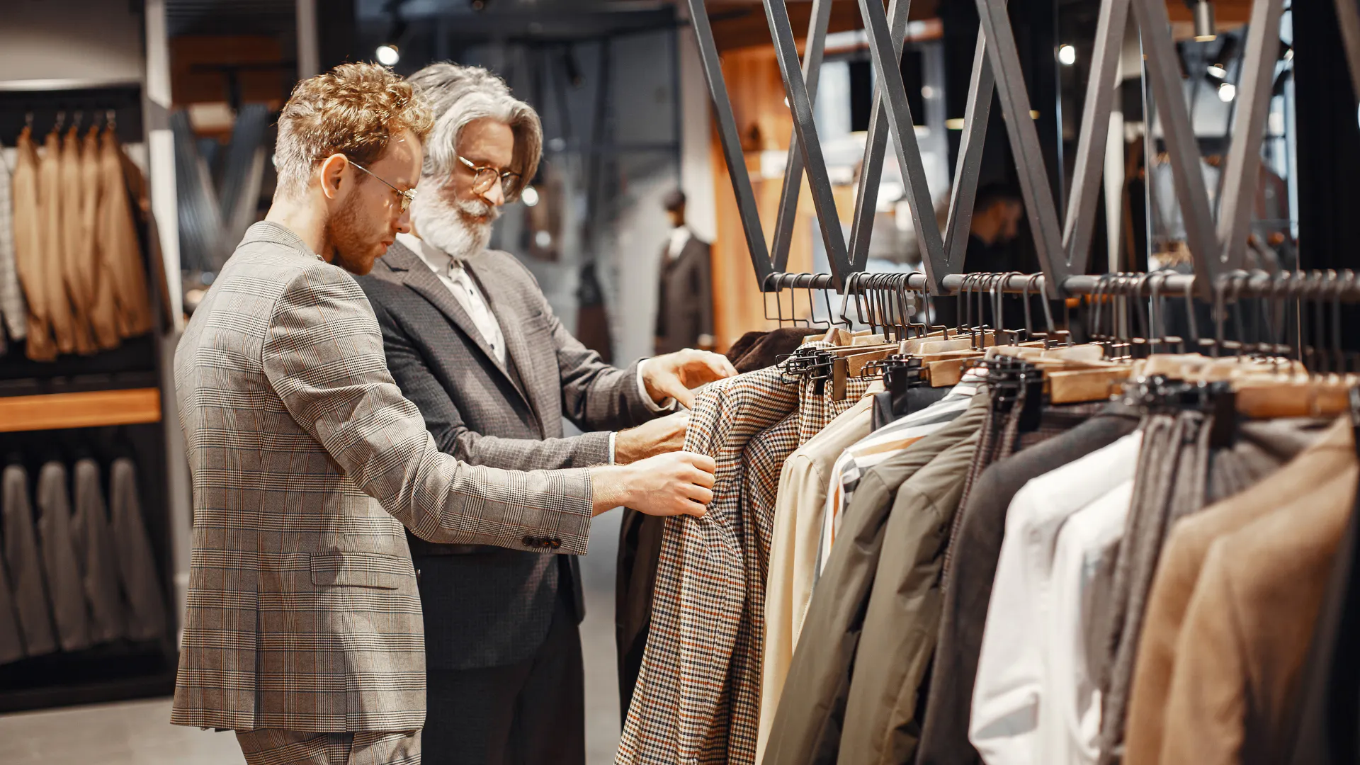 middle aged and younger man looking at suits in a store