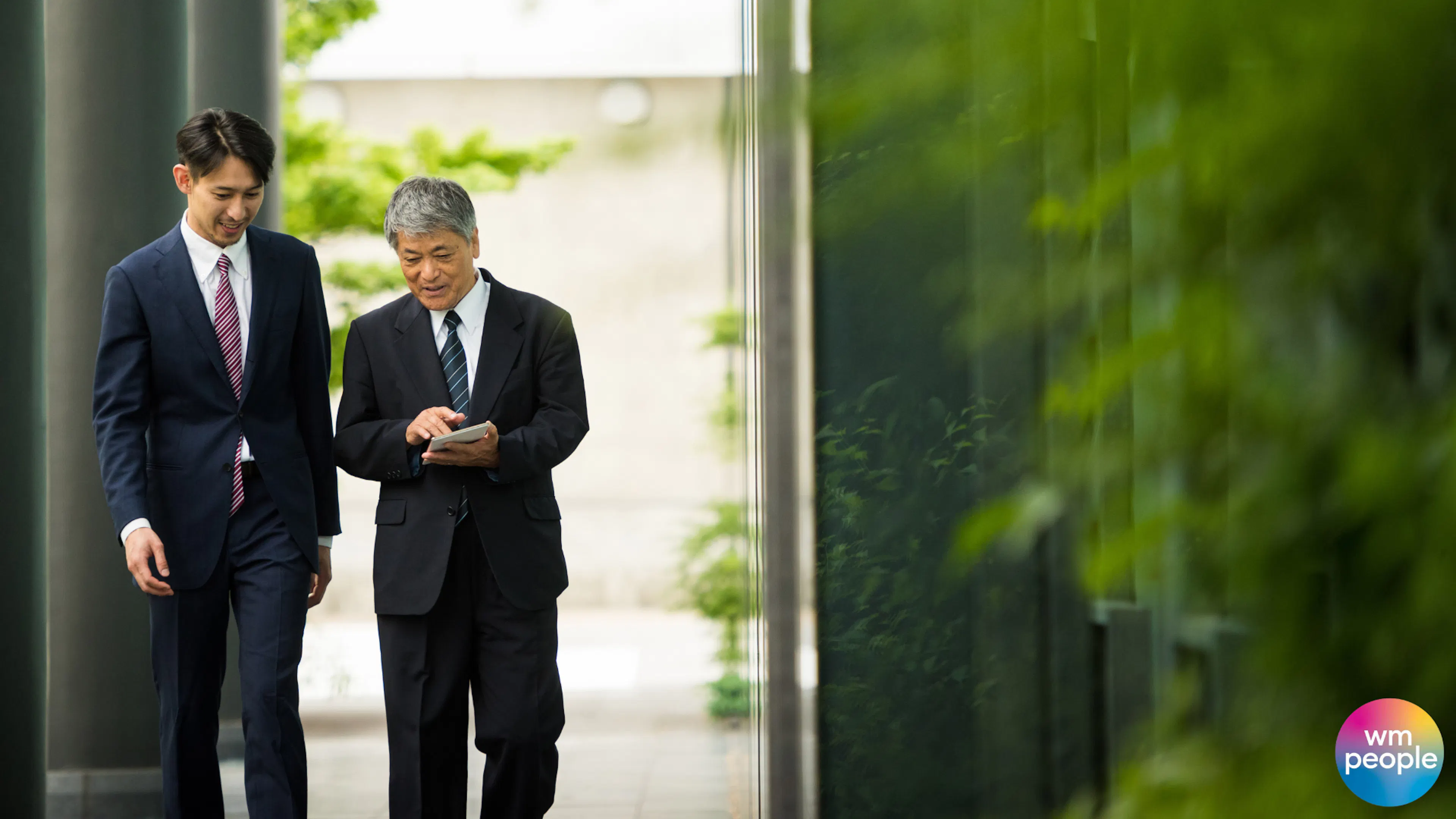 Two men in suits having meeting walking outdoors