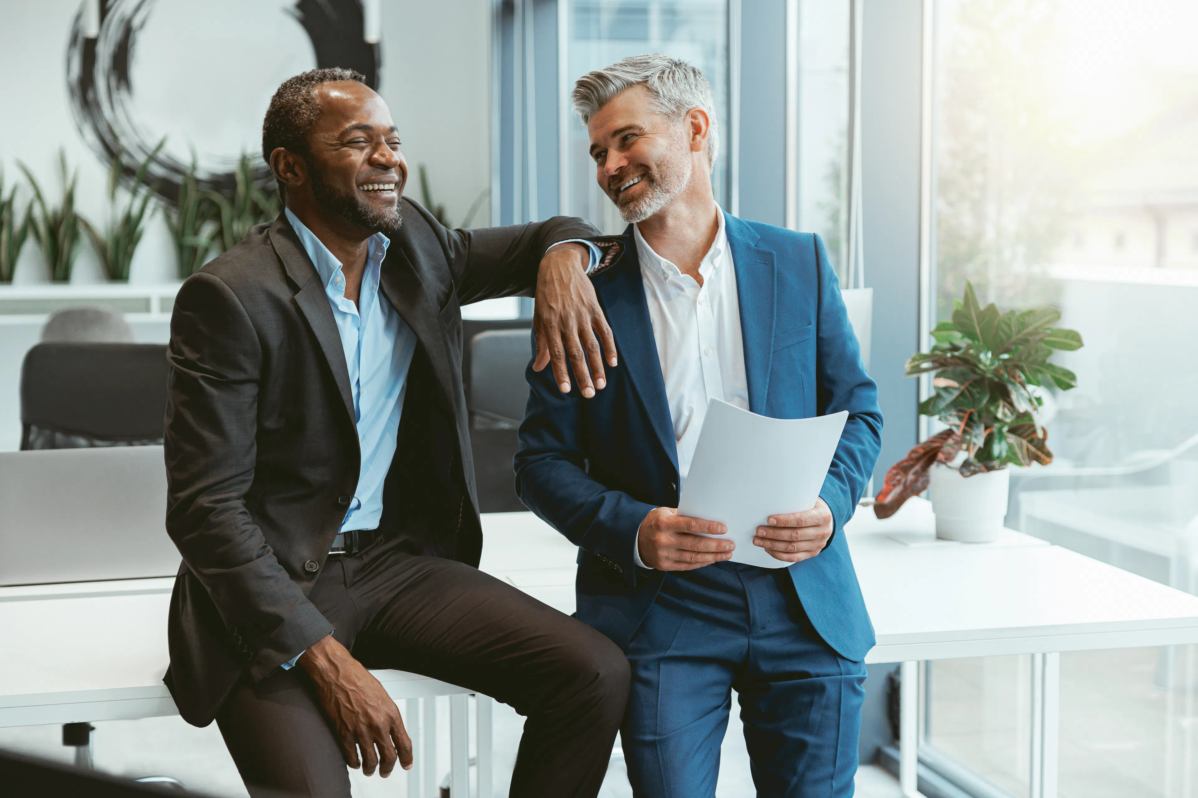 two-smiling-businessmen-talking-about-deal-sitting-meeting-room-modern-office