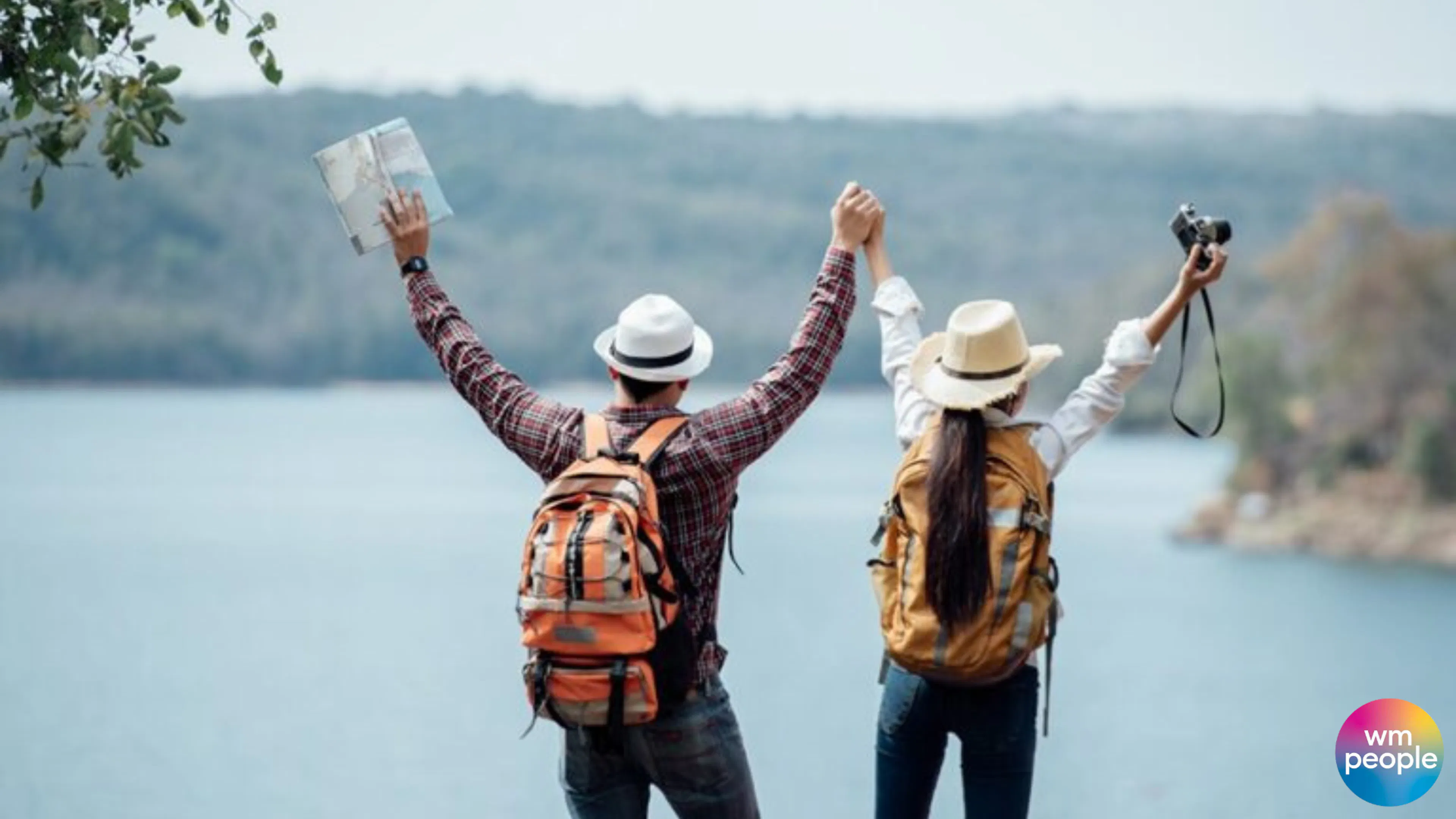 Couple hiking, arms stretched up in happiness
