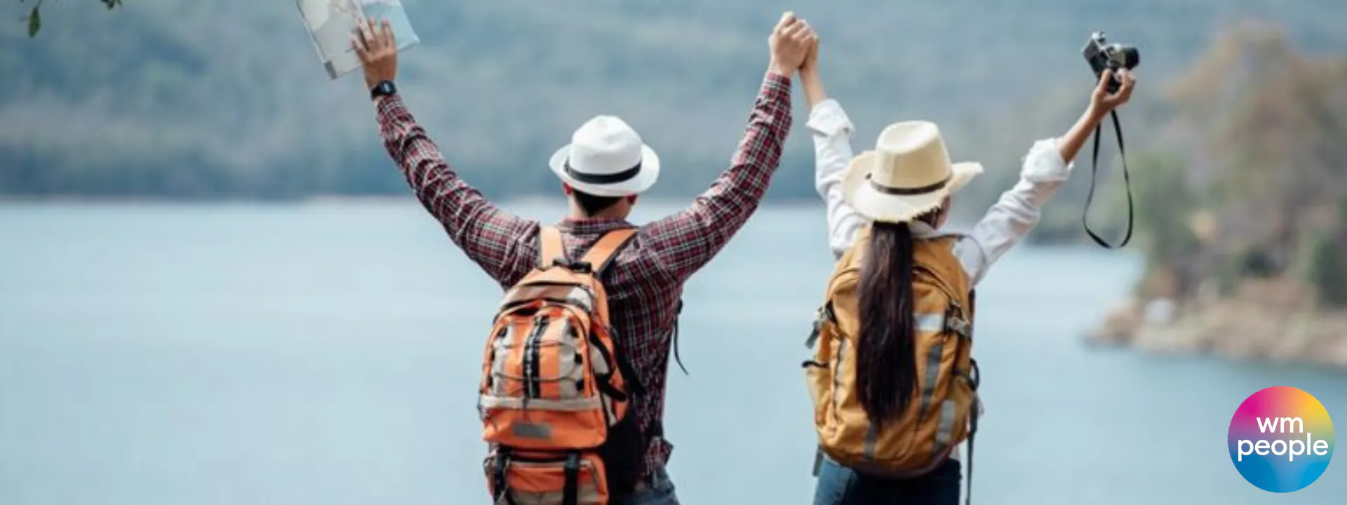Couple hiking, arms stretched up in happiness