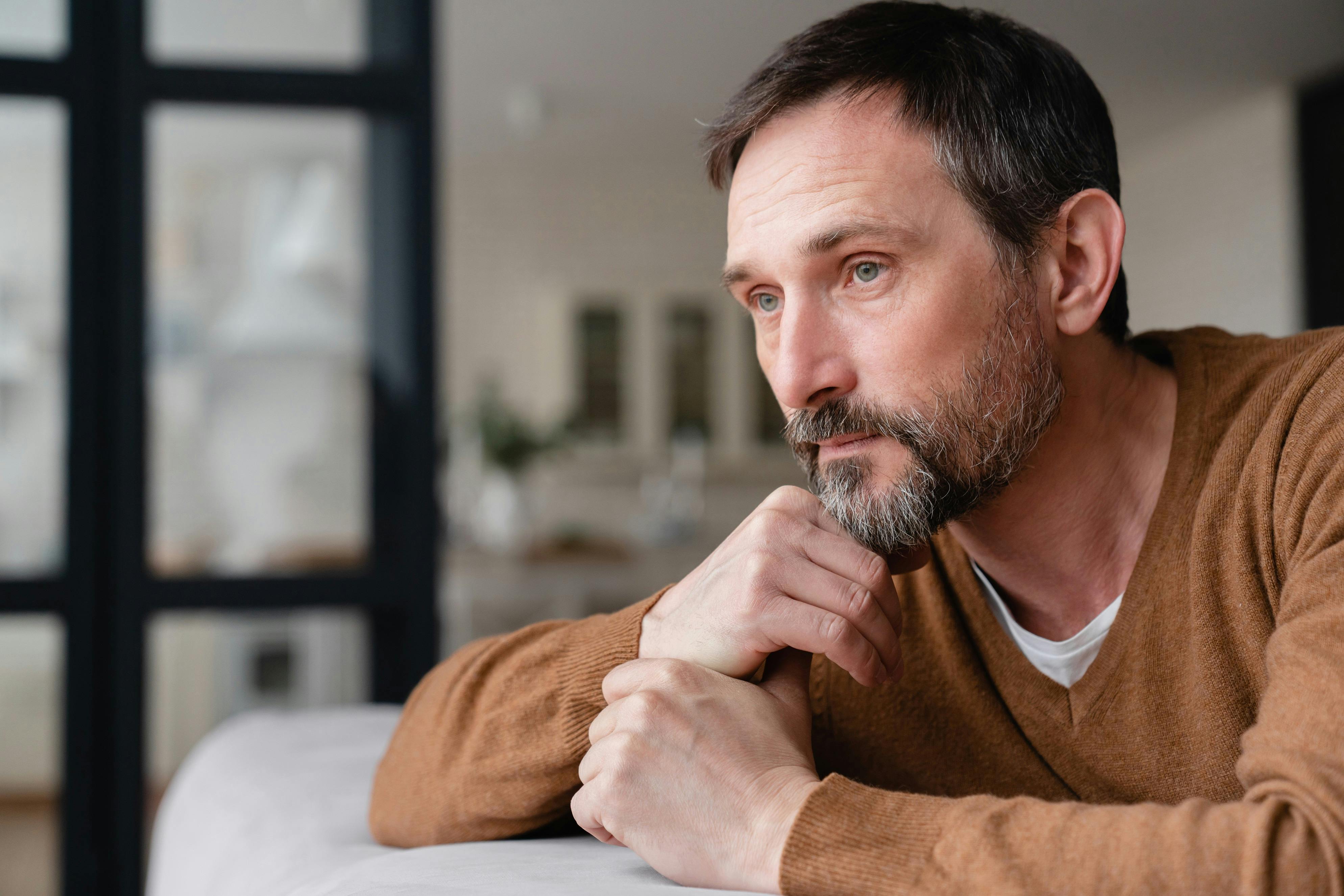 sad mature man leaning to side with hand on chin