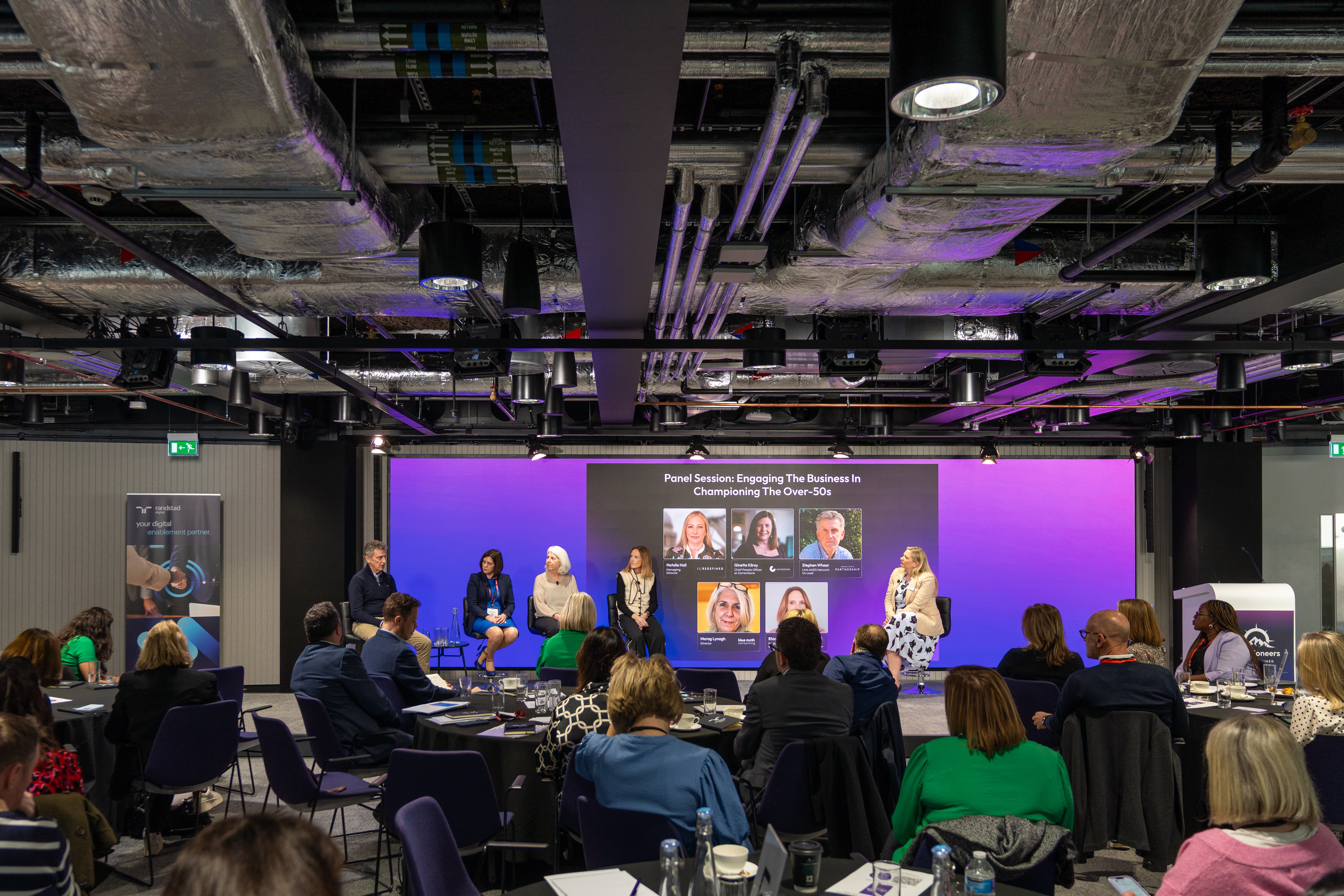 Panel speaking on stage at Age Pioneers
