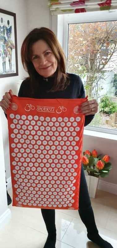 Hilda Smith holding a red shakti mat with white spikes