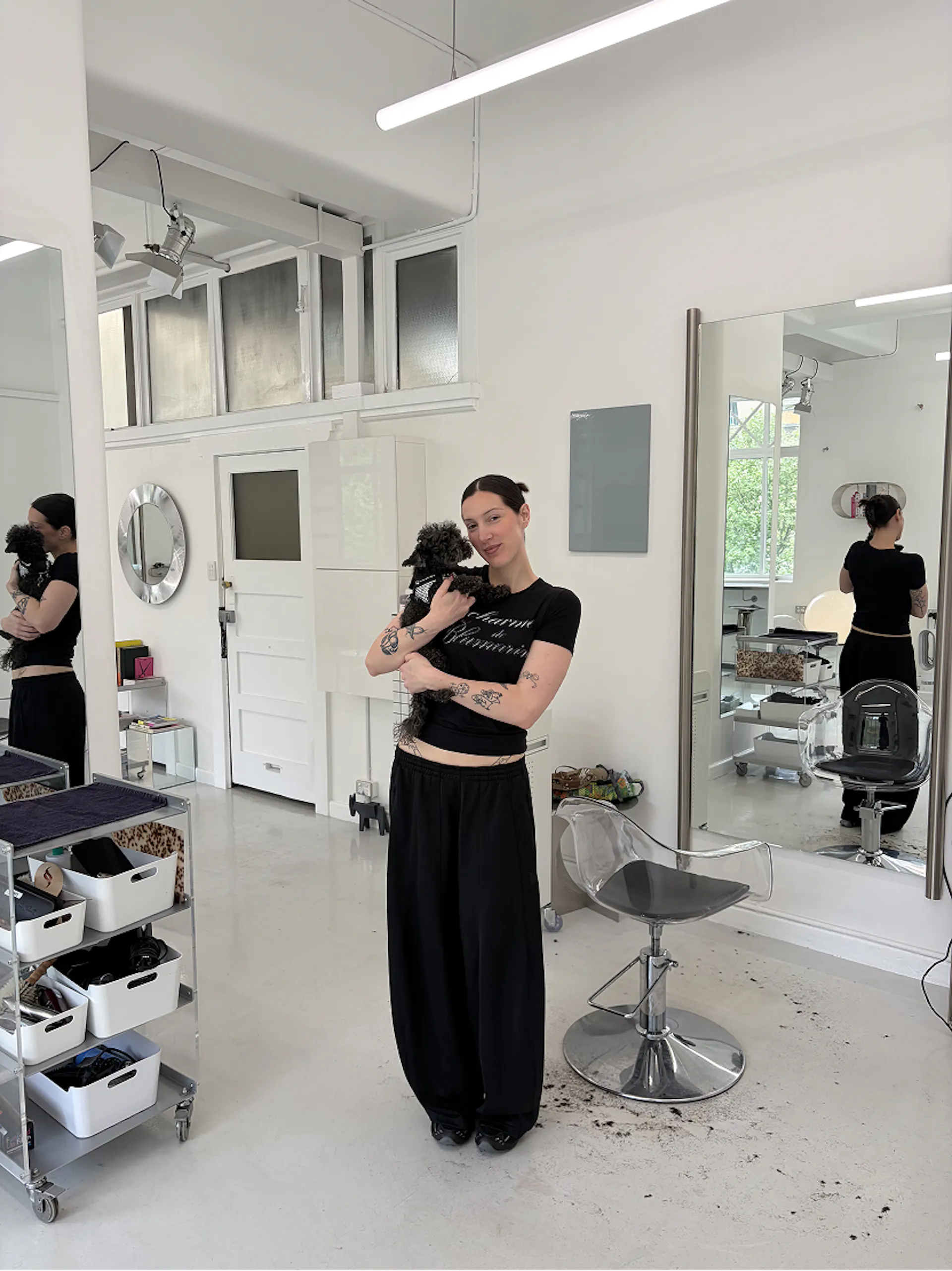 Stylist holding a small black dog in the bright white Star Studio salon