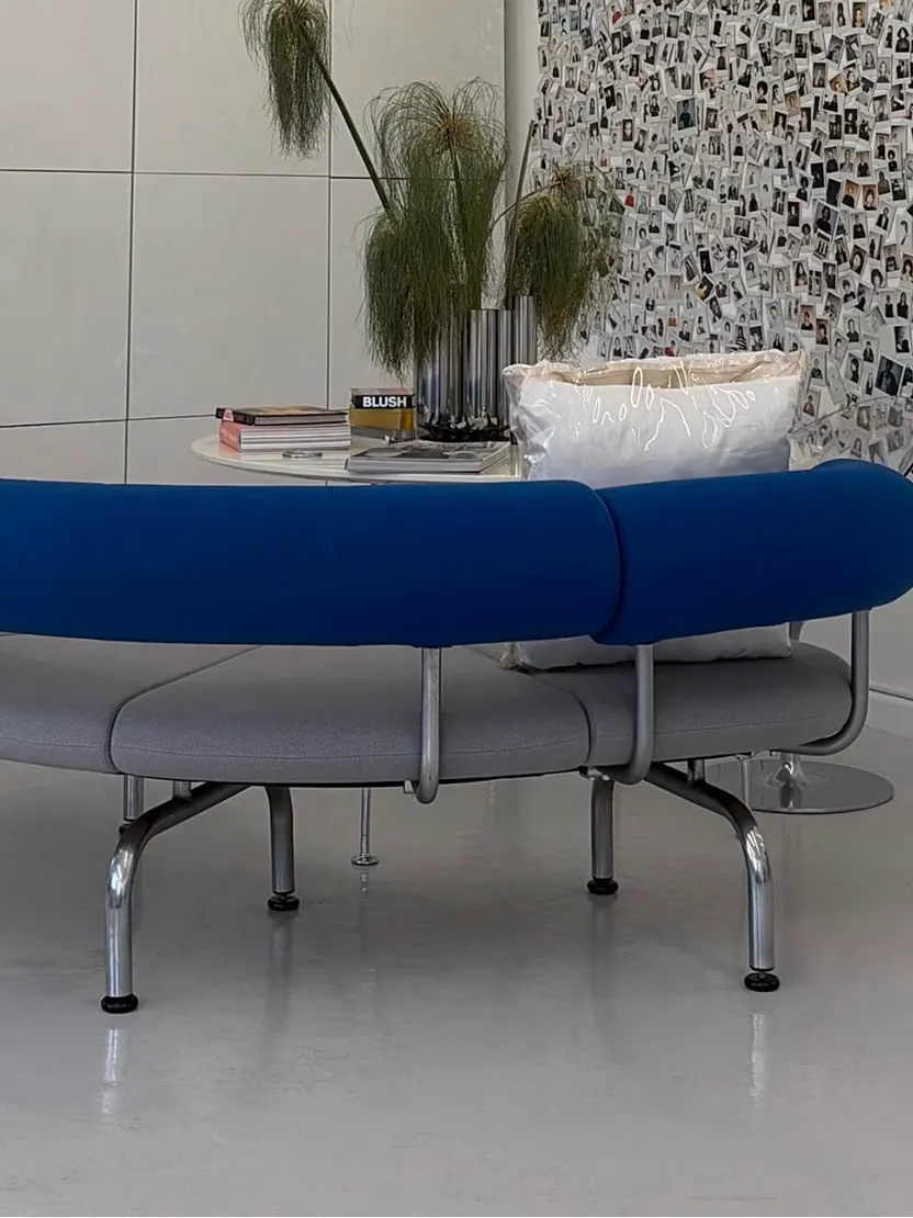 Curved blue bench in front of a wall of polaroid photos