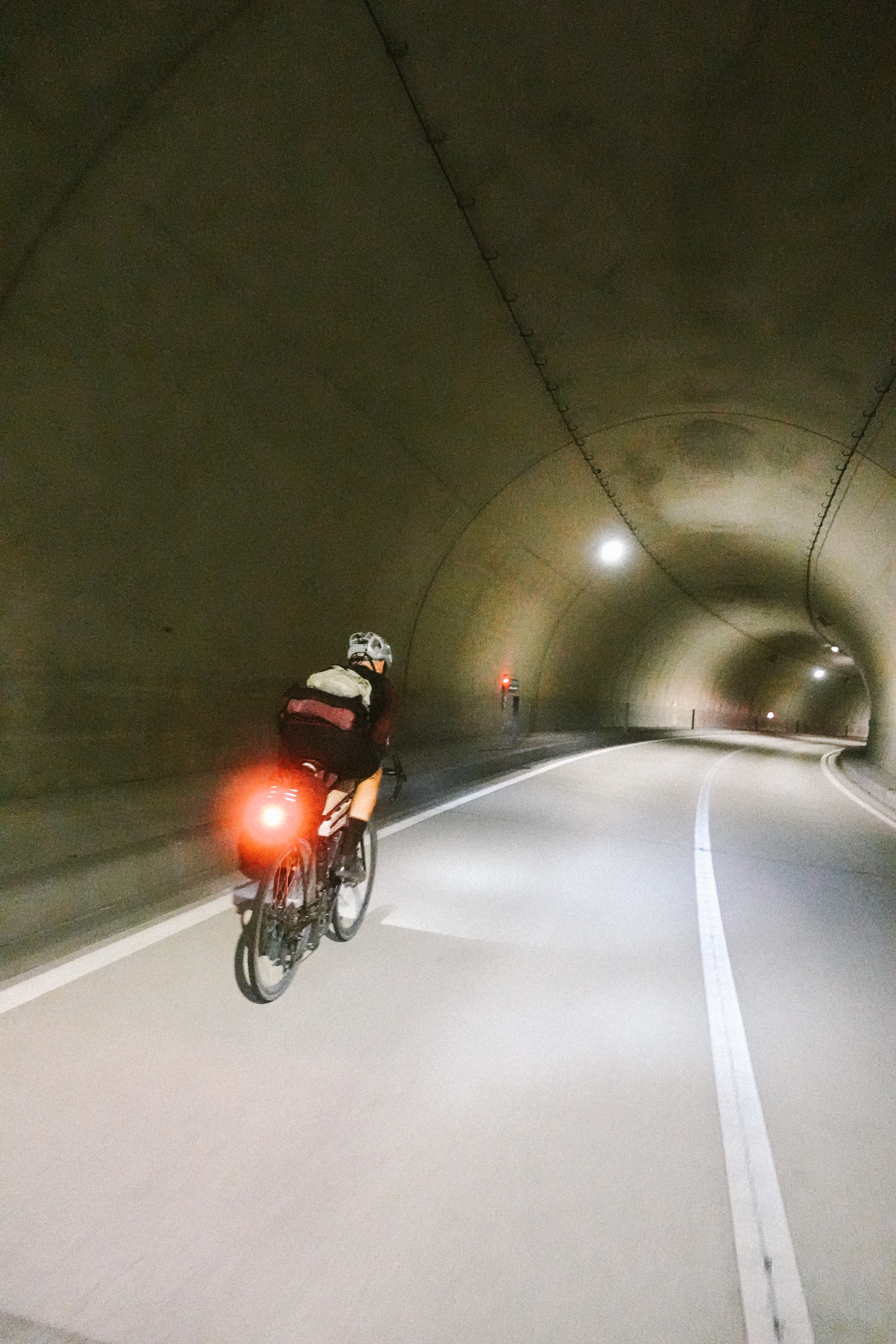 Rider with a red rear light in a curved road tunnel