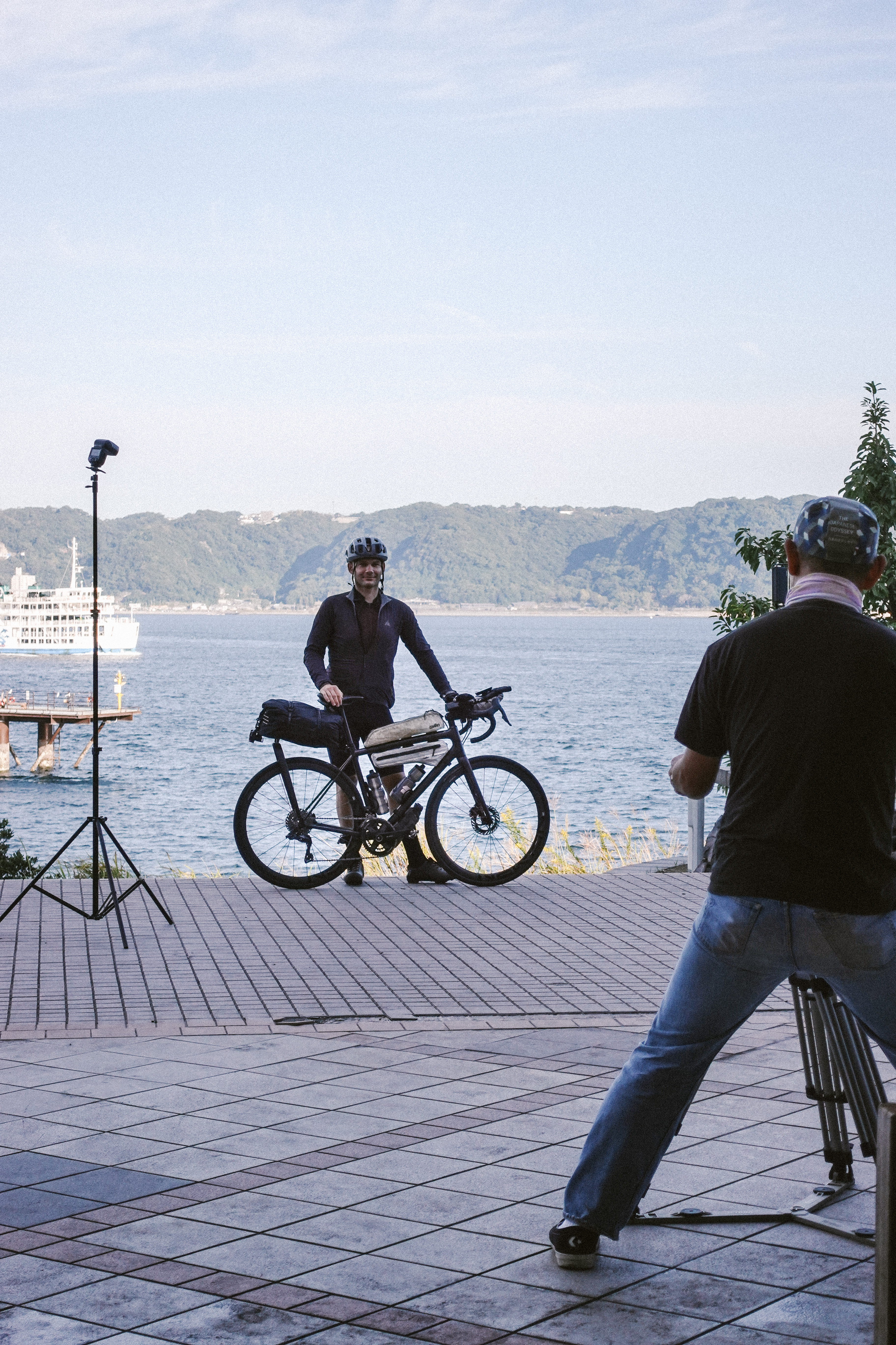 Rider with a loaded bike posing for a photographer at a harbour before the start