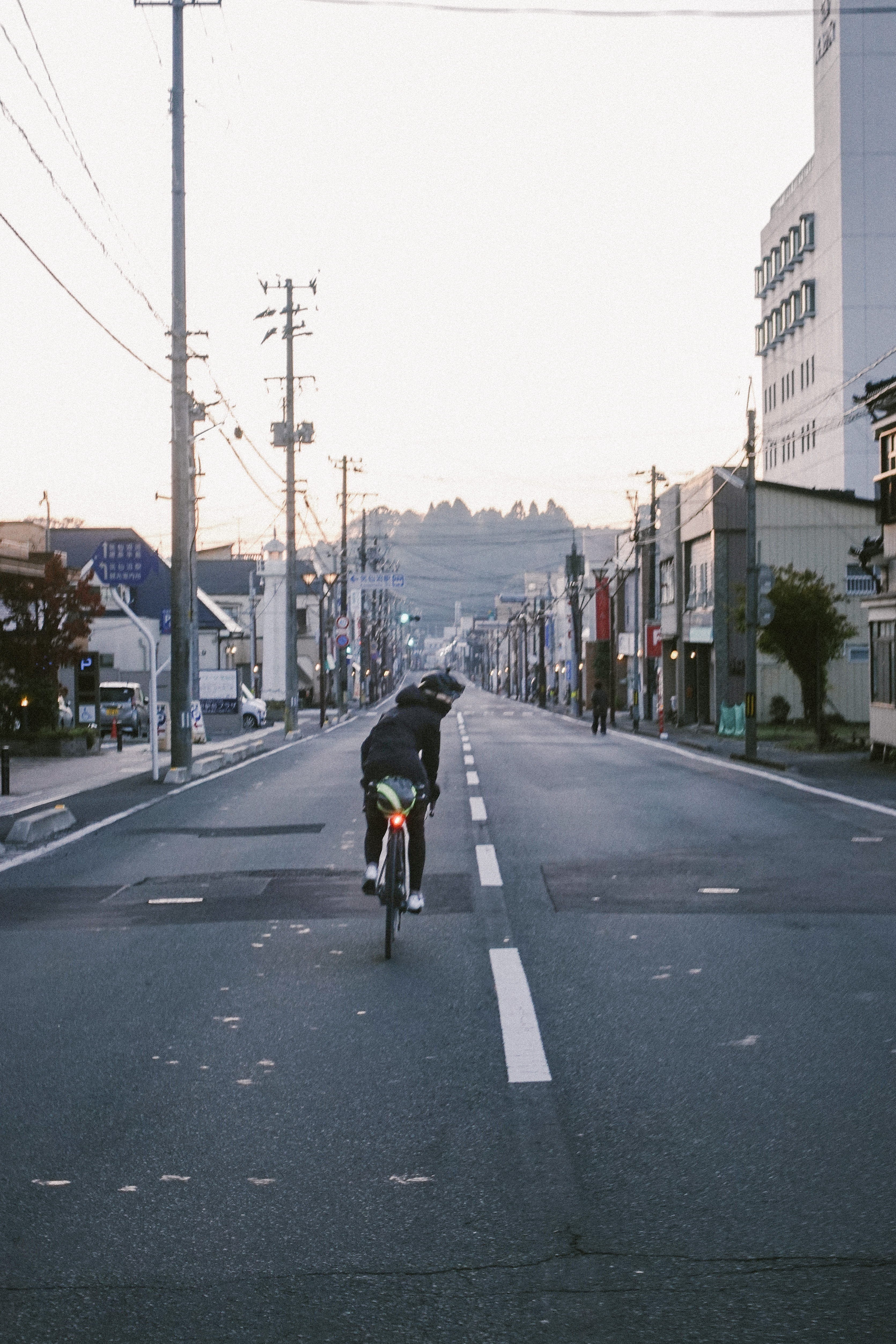 Rider on an empty town street at dawn with jagged peaks in the distance