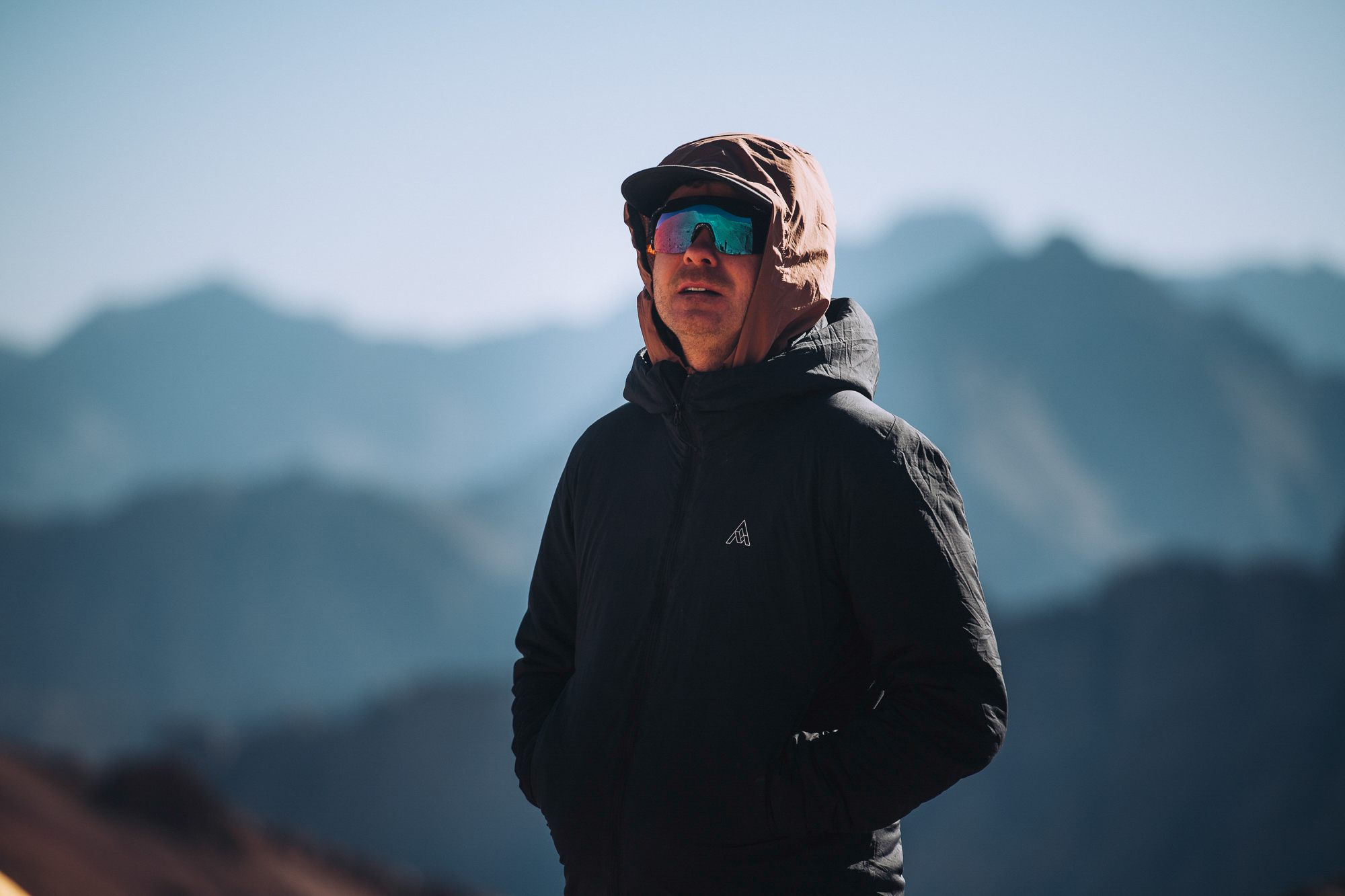 Portrait of a rider in a hood and sunglasses against hazy blue mountains