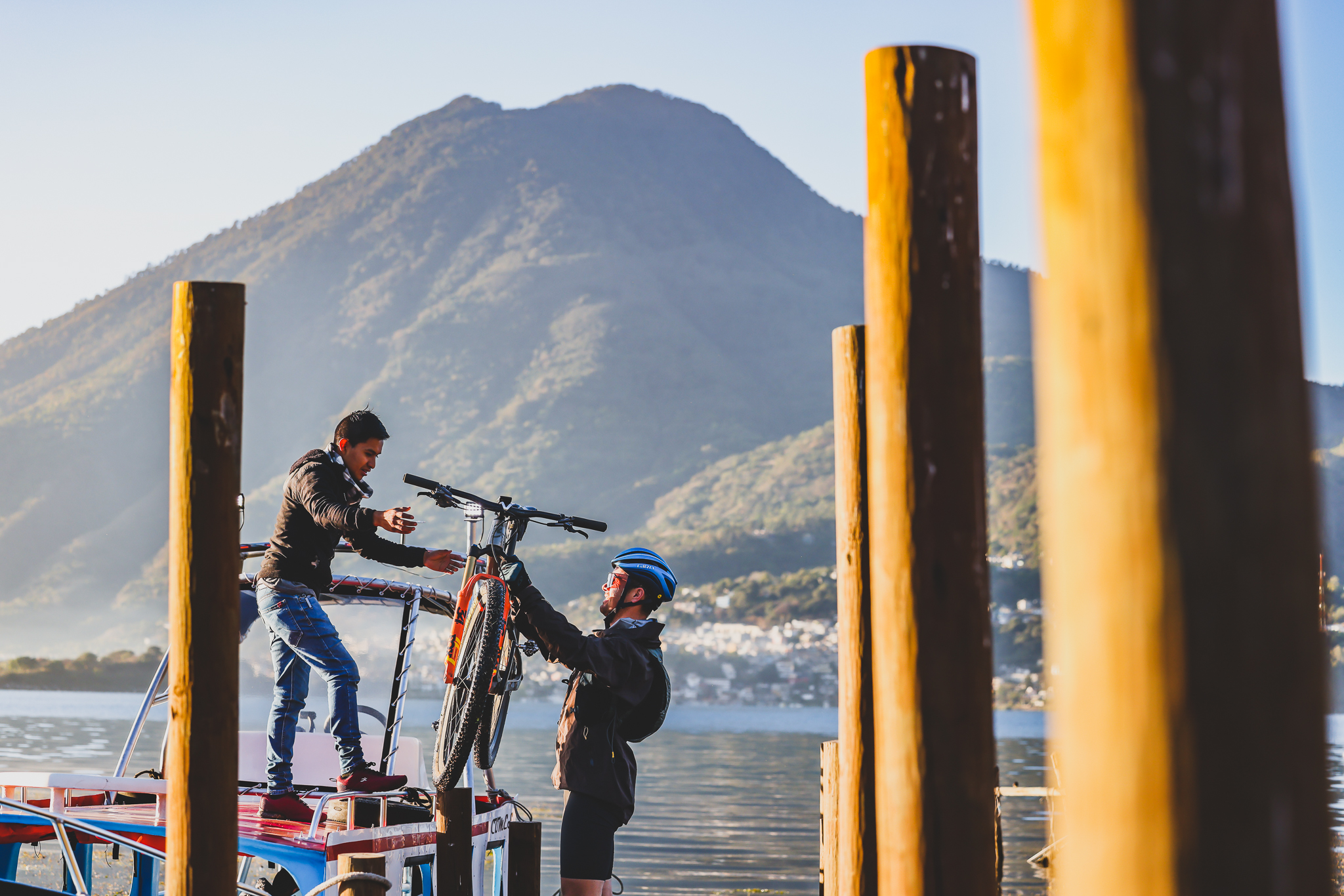 A mountain bike being handed down from a boat roof to a rider on a jetty