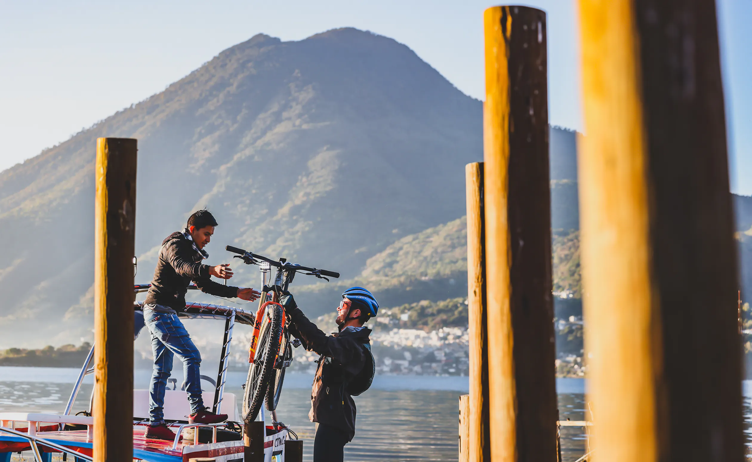 A mountain bike being handed down from a boat roof to a rider on a jetty