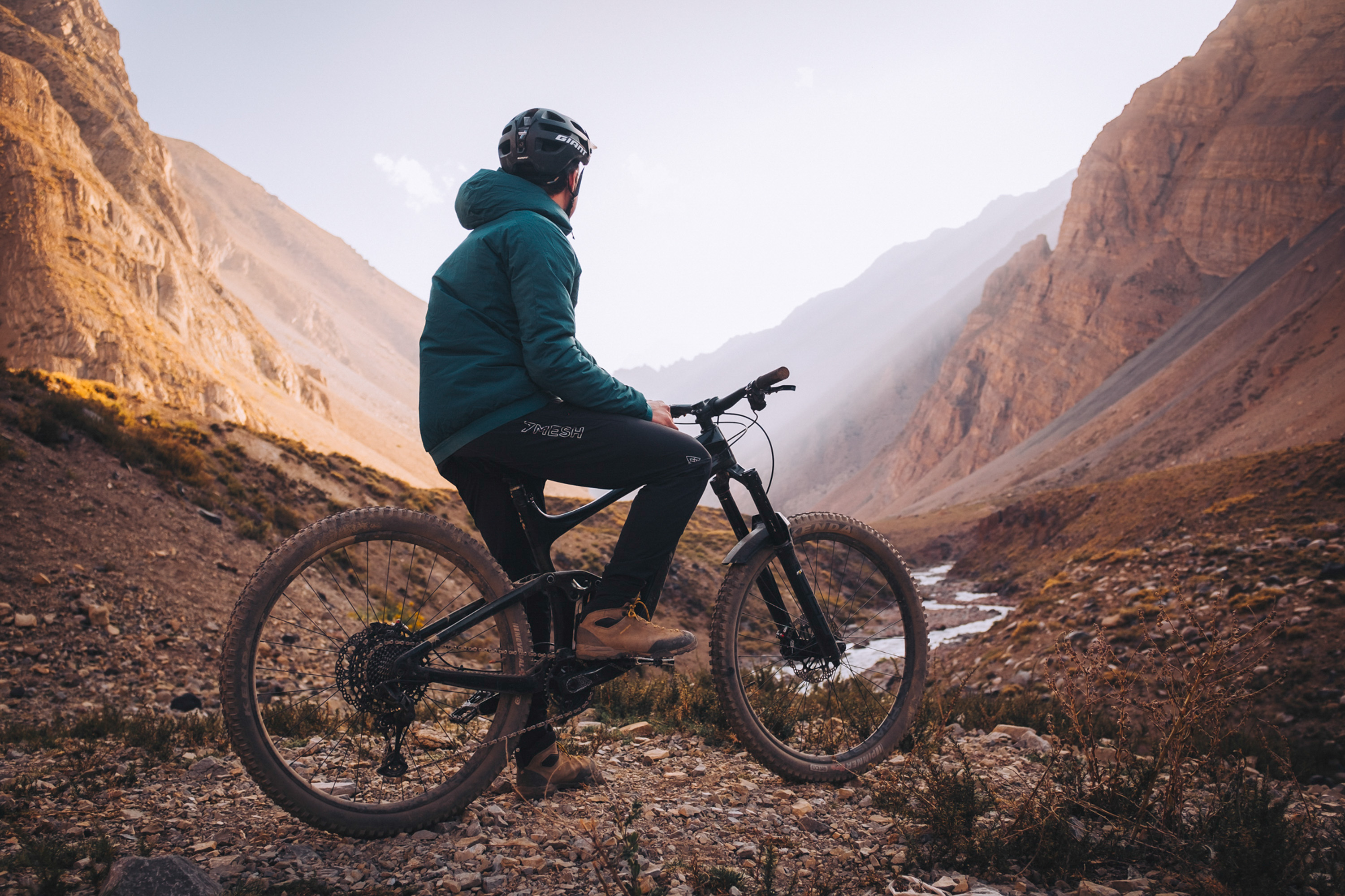 Rider on a bike looking down a deep dry canyon at sunrise
